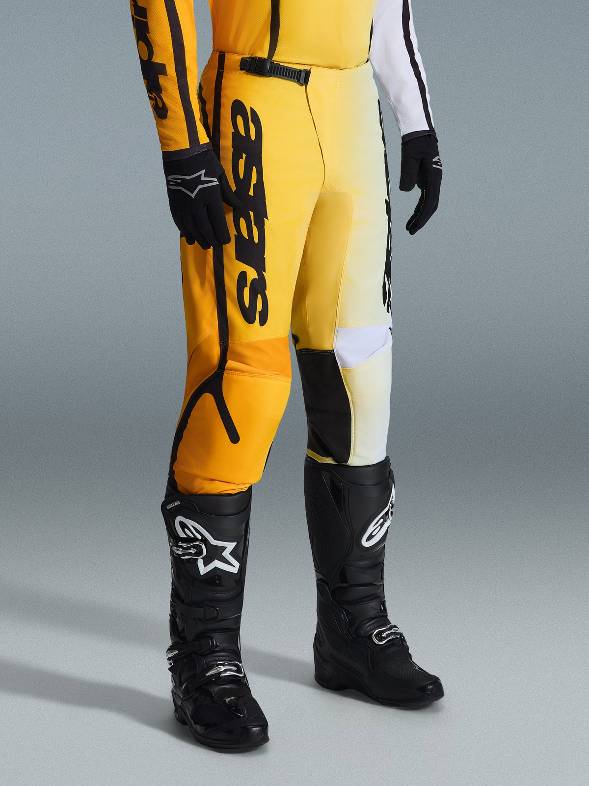 Alpinestars 2026 Fluid Apex bukser, motocrossbukser, gul og sort, bæres med sorte støvler og handsker, markant 'astars' branding på låret, ergonomisk design med forstærkede paneler, slidstærkt materiale til off-road kørsel
