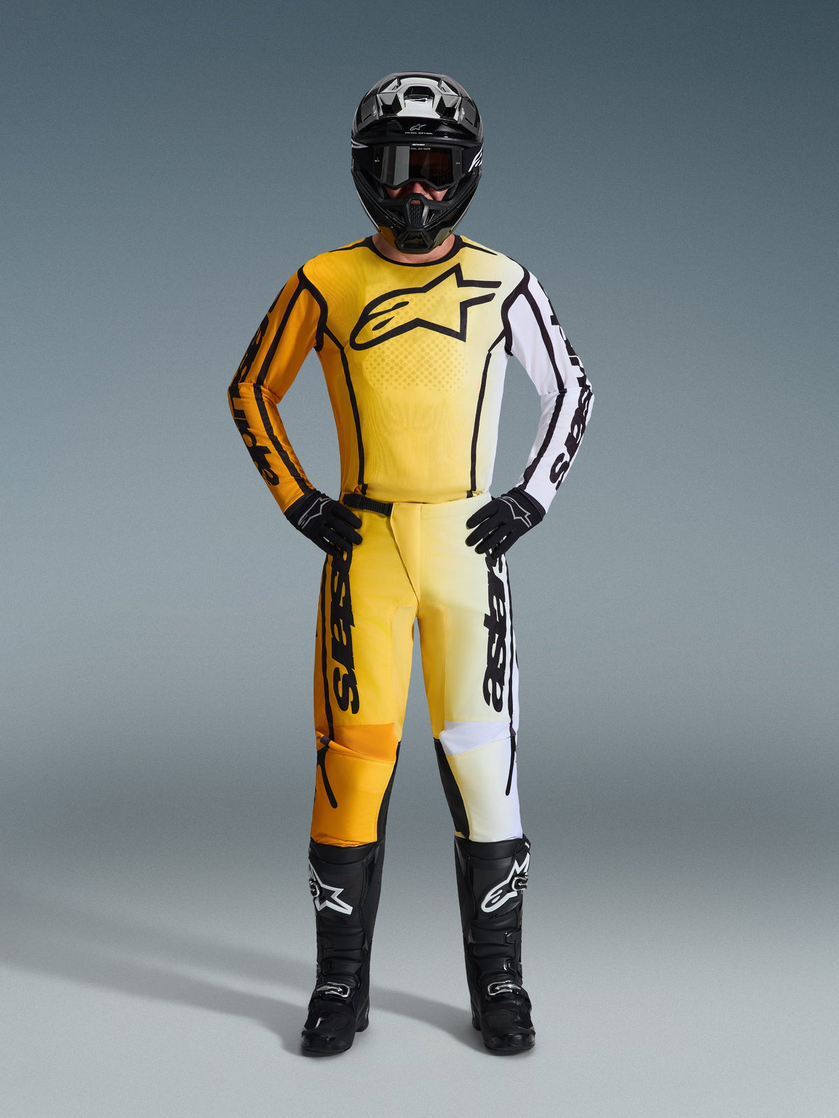 Alpinestars 2026 Fluid Apex bukser, motocrossbukser i gul, sort og hvid, båret som et komplet racersæt med matchende gradient-jersey, sort hjelm og støvler, professionelt off-road køreudstyr