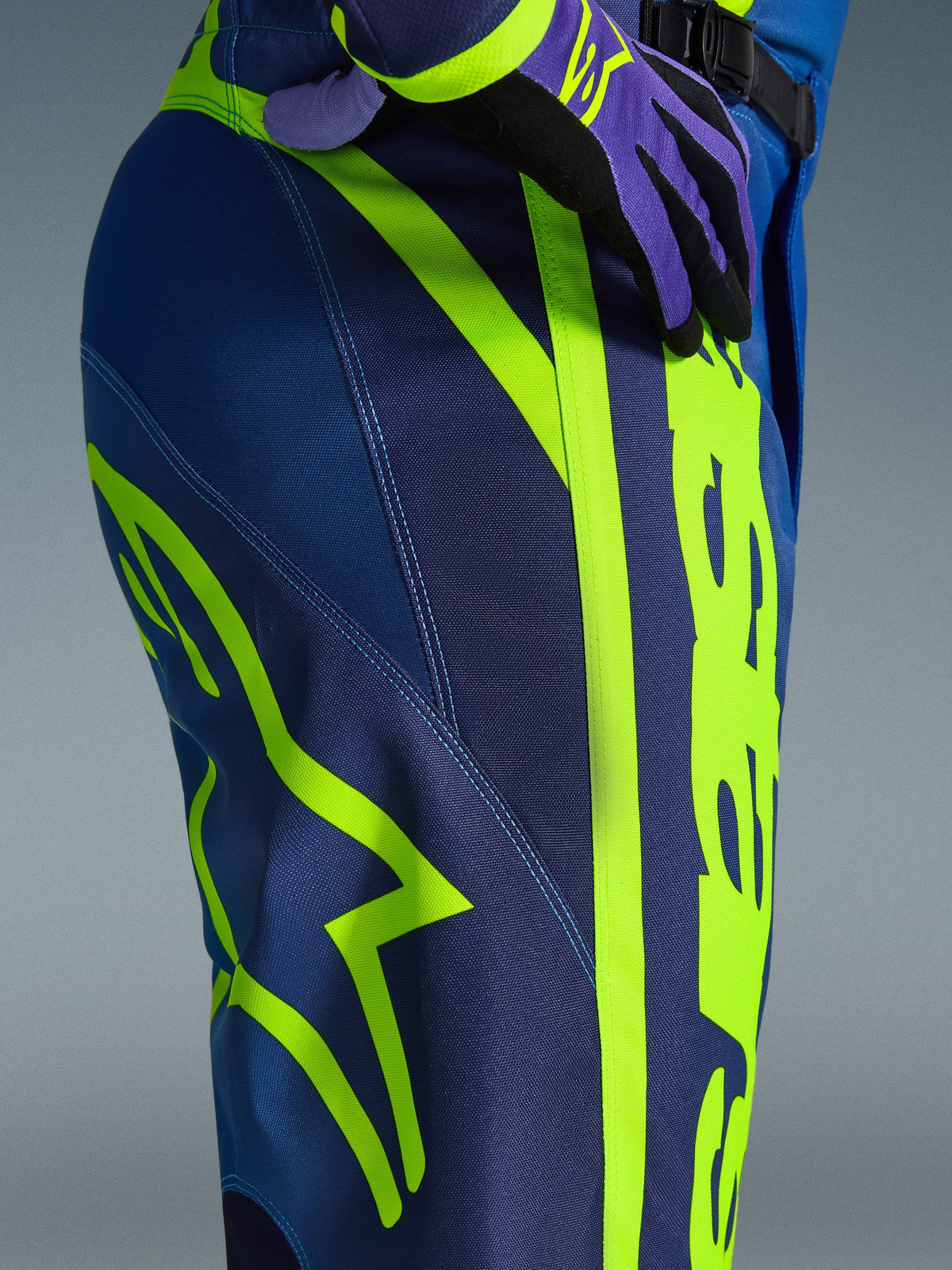 Alpinestars 2026 Fluid Apex bukser, motocrossbukser, blå og neongul, nærbillede af siden og hoften med markant neongult Alpinestars-logo, holdbart polystof-materiale til off-road kørsel, del af matchende udstyrssæt
