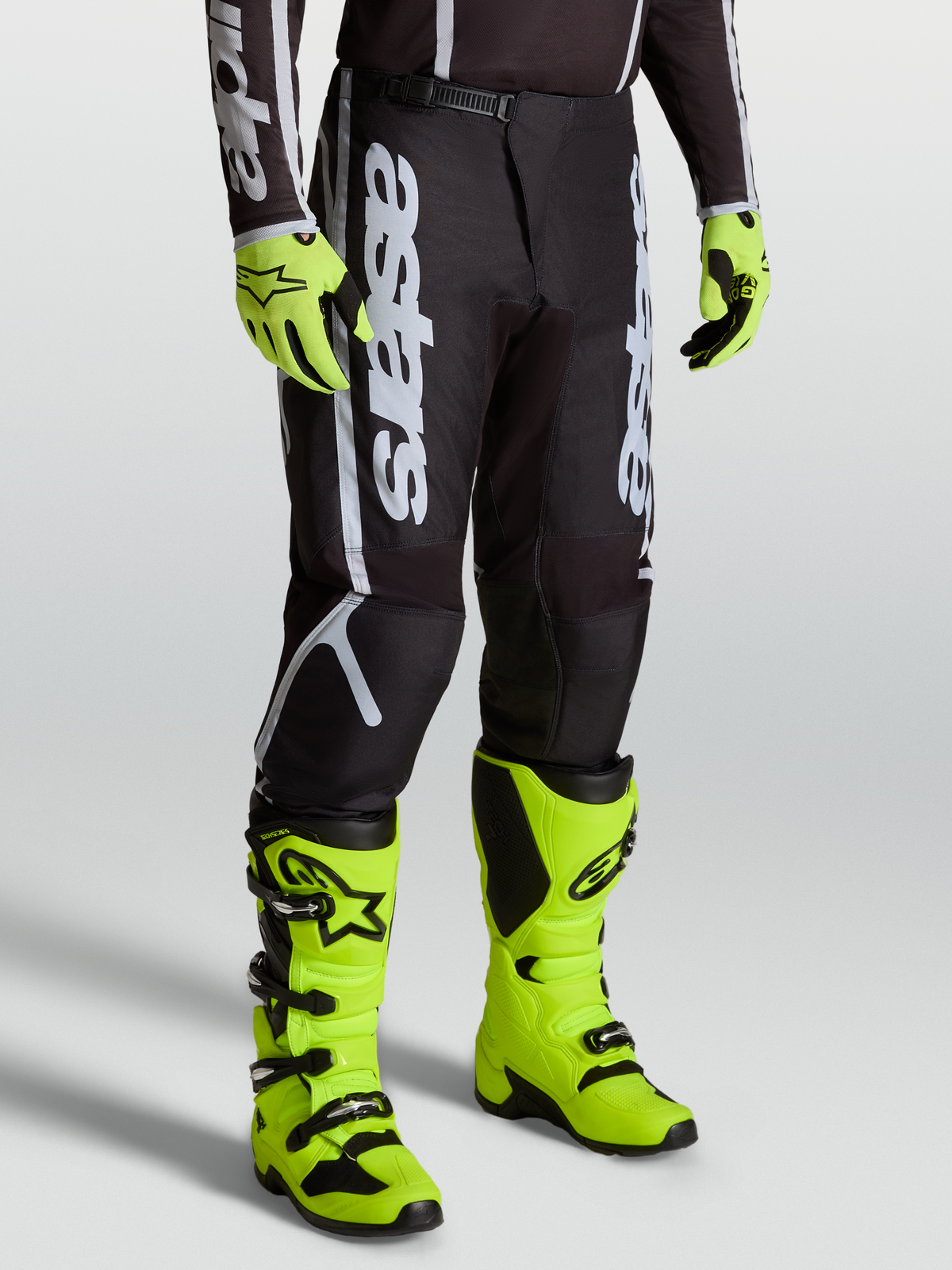 Alpinestars Fluid Apex V2 bukser, herre MX bukser, sort og sølv, slidstærk 600D polyfabric, vist med gule støvler