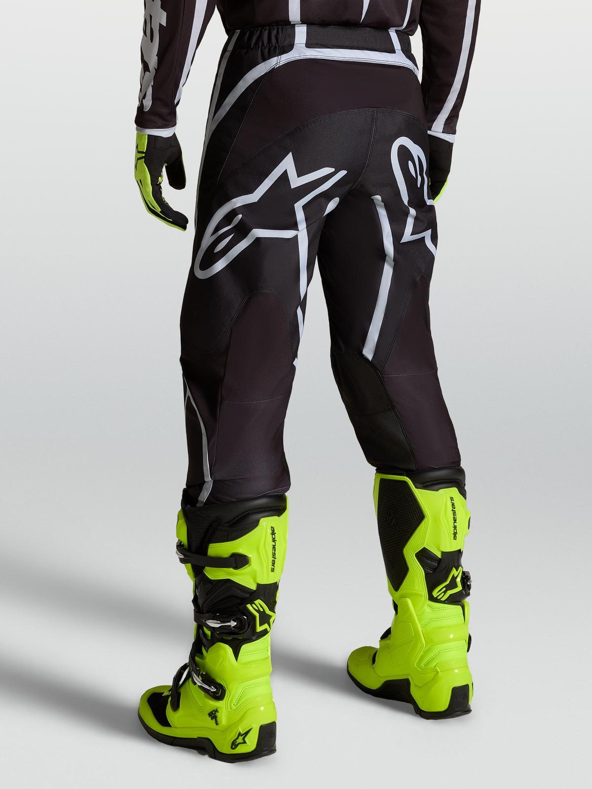 Alpinestars Fluid Apex V2 Bukser, motocrossbukser til mænd i sort og sølv, båret med gule støvler, bagfra