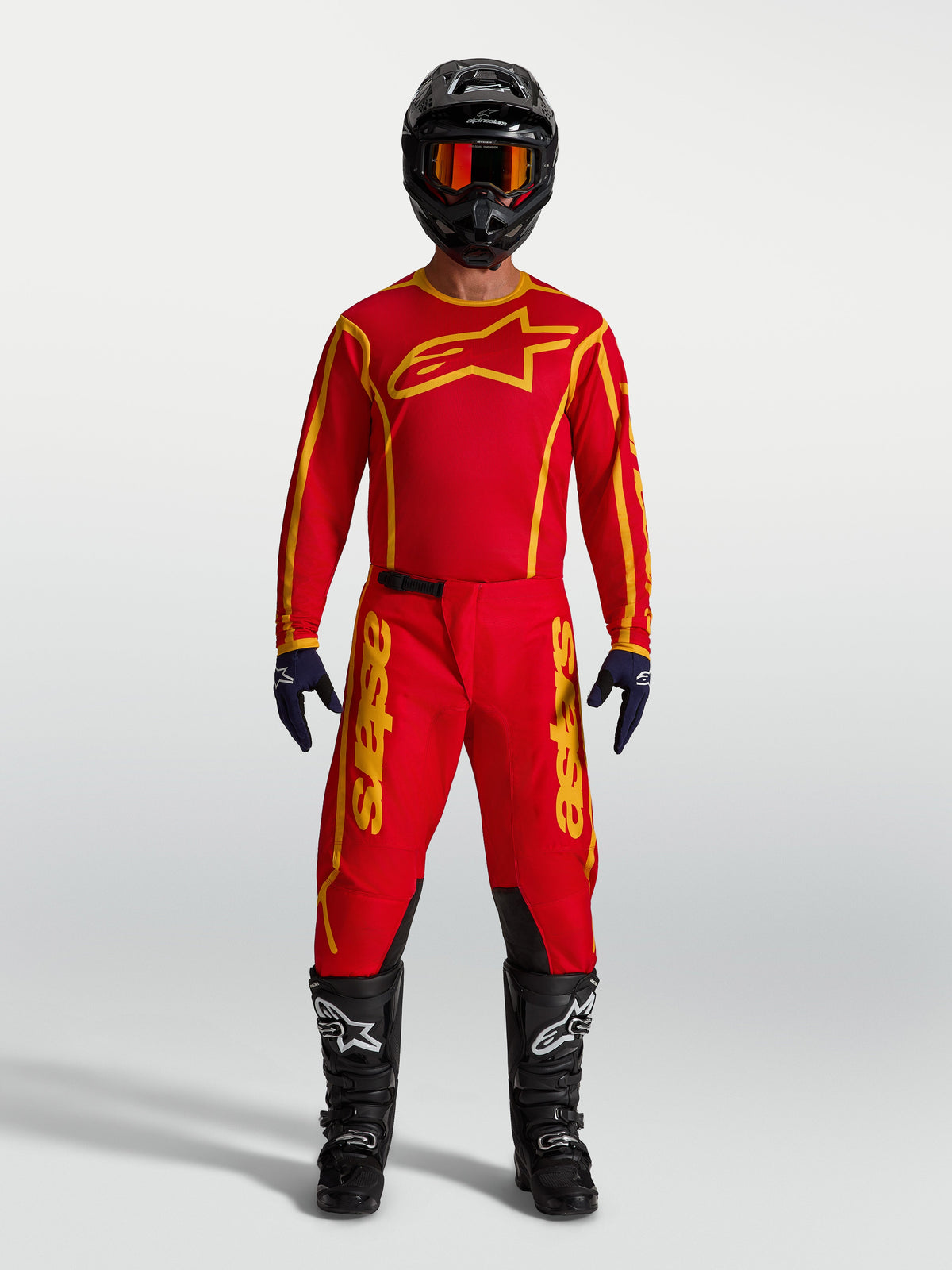 Alpinestars Fluid Apex V2 bukser til herrer, rød og guld motocrossudstyr med matchende trøje, sort hjelm og støvler.