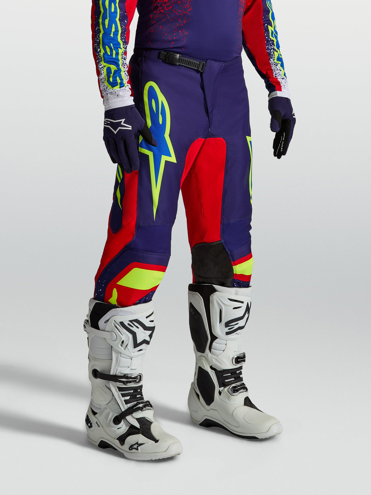 Alpinestars Fluid Drag bukser, mørkeblå og røde herre-motocrossbukser med grafik, båret med hvide motocrossstøvler.