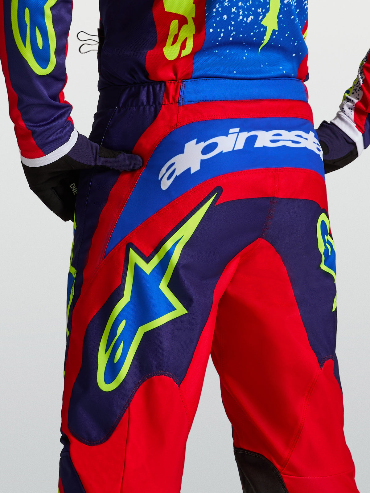 Alpinestars Fluid Drag bukser, blå og røde motocrossbukser med gul stjerne-grafik bagpå og sportspasform.