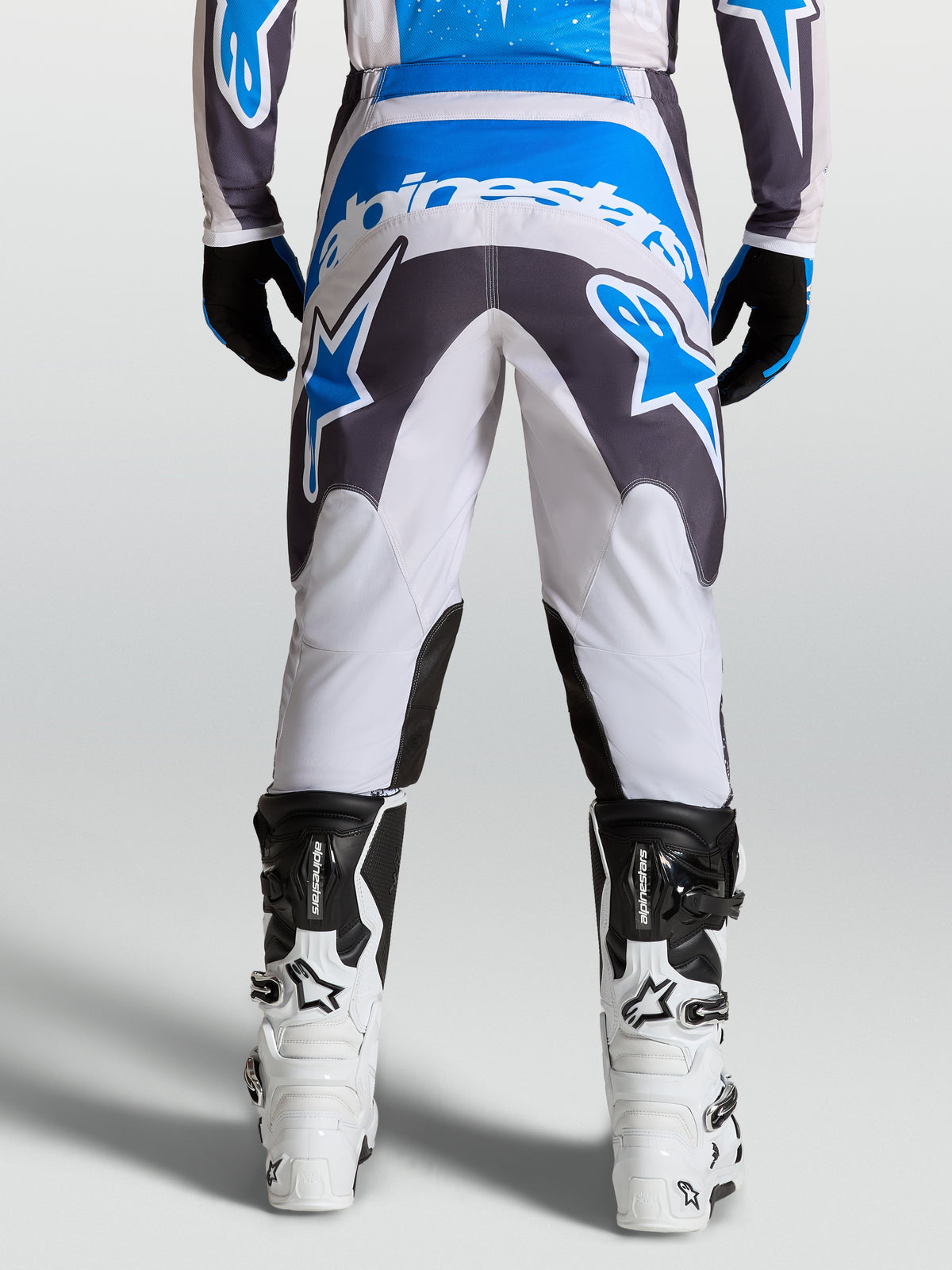 Alpinestars Fluid Drag Bukser, herre-motocrossbukser i grå og blå med forstærket sæde, set bagfra til terrænkørsel.