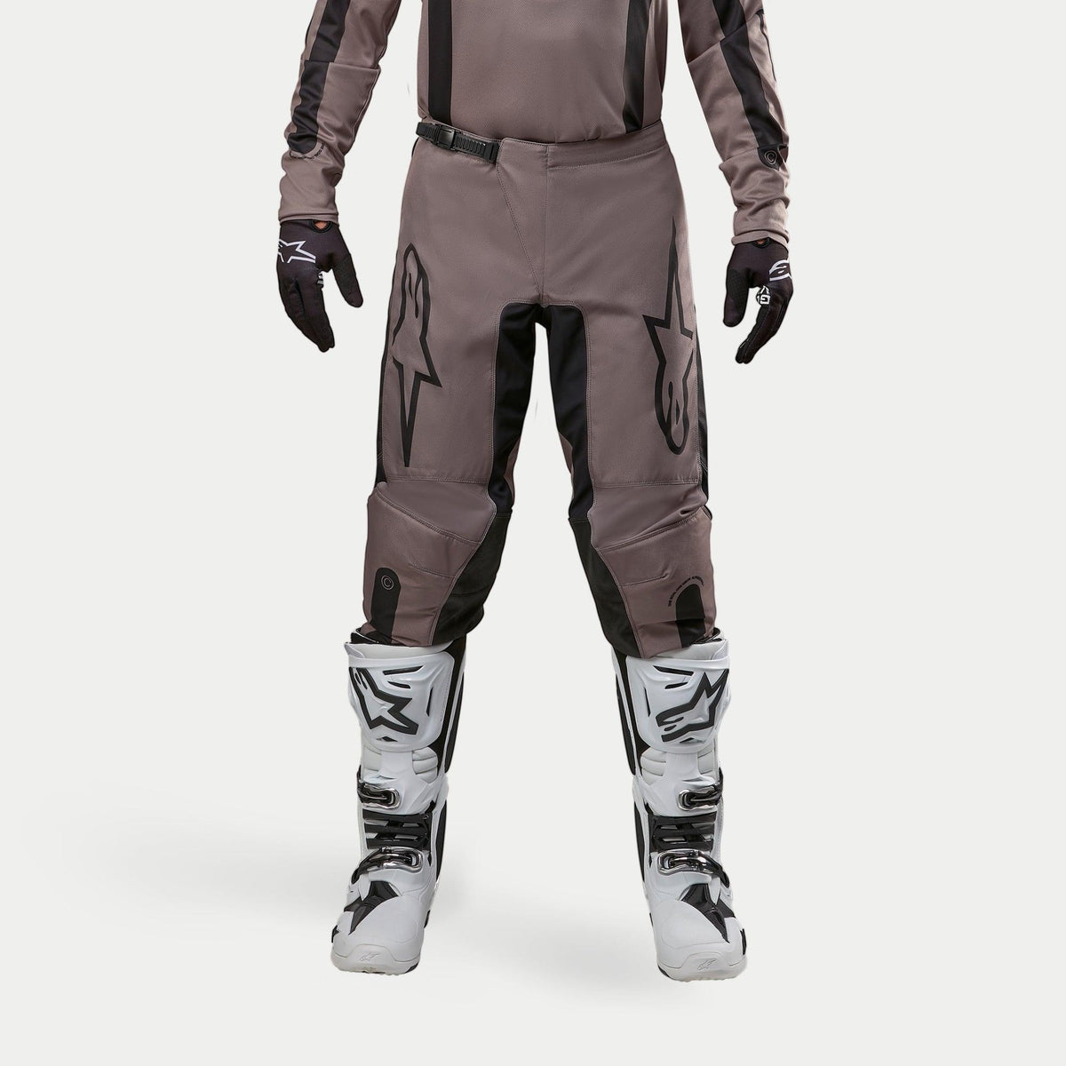 Alpinestars 2024 Fluid Lurv Pants, Motocross Pants, Mud Black, worn with matching jersey, black gloves, and white boots, featuring large black logos on thighs, ergonomic fit, and durable material for off-road racing