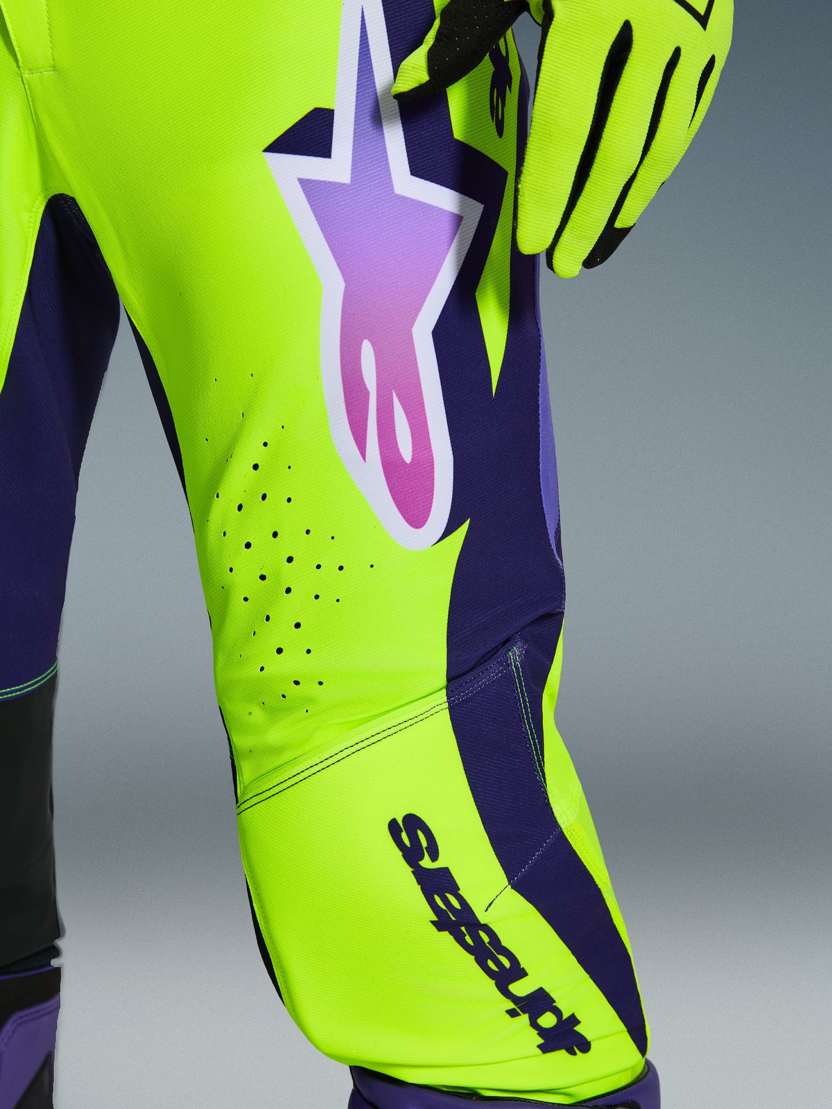 Alpinestars 2026 Supertech Vista Pants, Motocross Pants, Yellow Purple and Black, close-up showing gradient star logo and laser-cut ventilation holes, paired with matching racing gloves