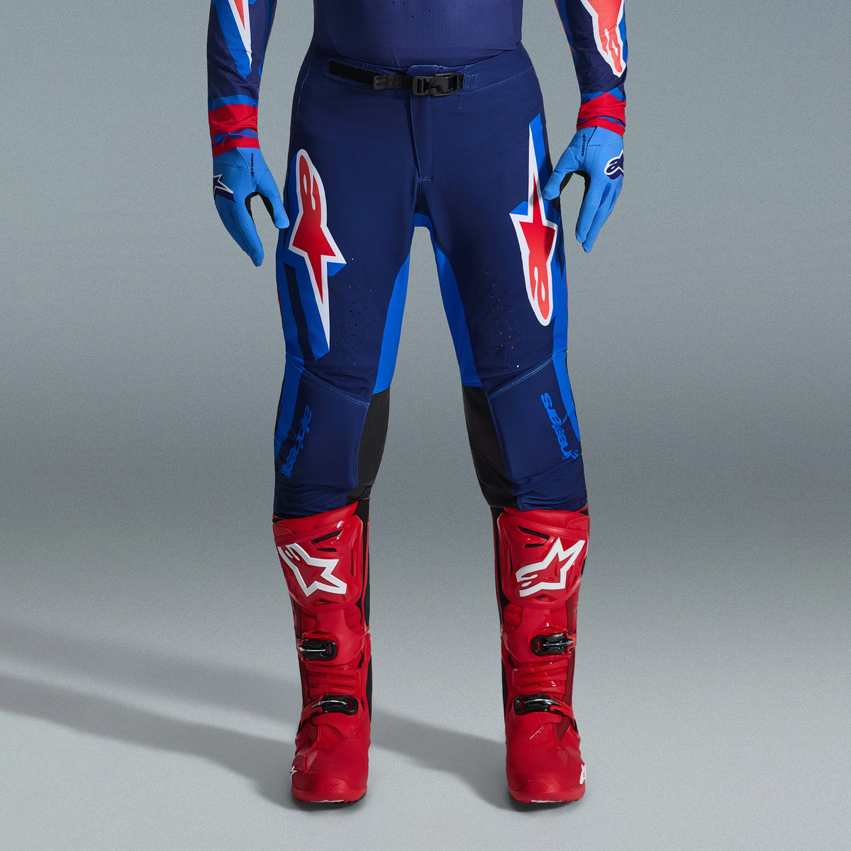 Alpinestars 2026 Supertech Vista udstyrssæt, motocrossbukser i navy og klar blå med røde og hvide logoer, kombineret med lyseblå handsker og klare røde motocrossstøvler, professionelt racerudstyr.