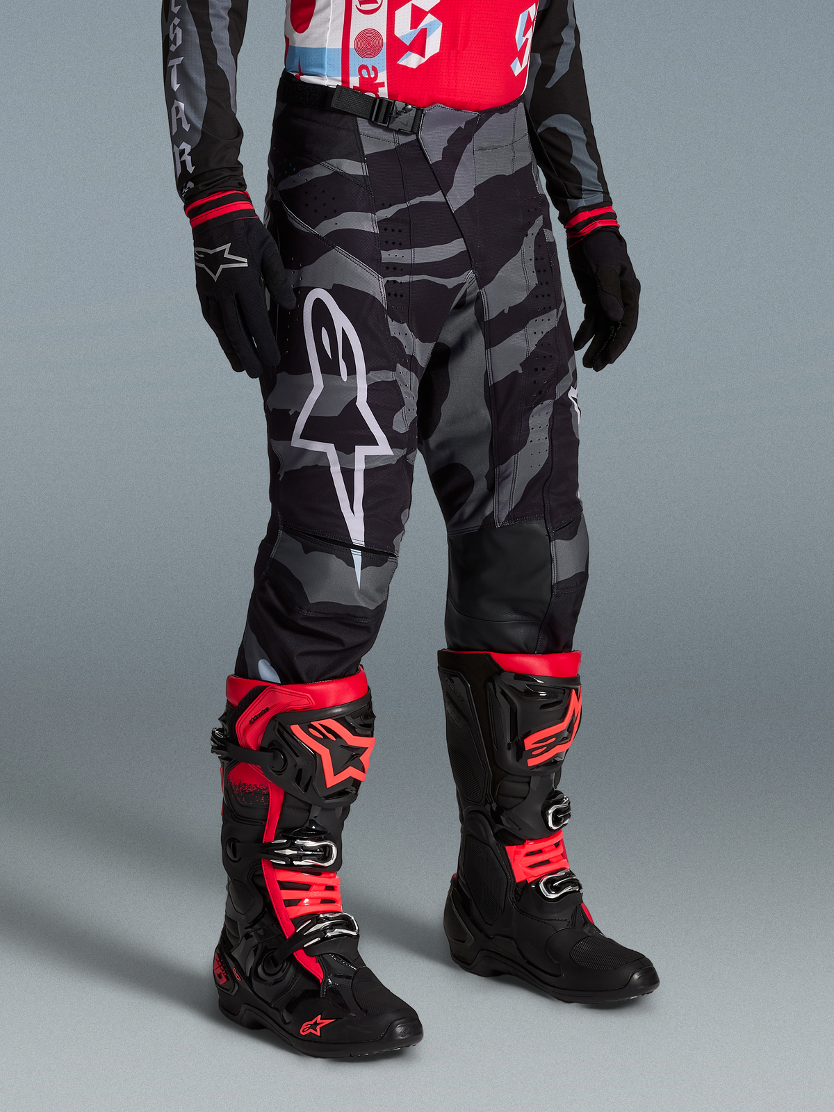 Alpinestars Techstar Beast Coast bukser i grå camouflage, vist med sorte og røde motocross-støvler til off-road kørsel.