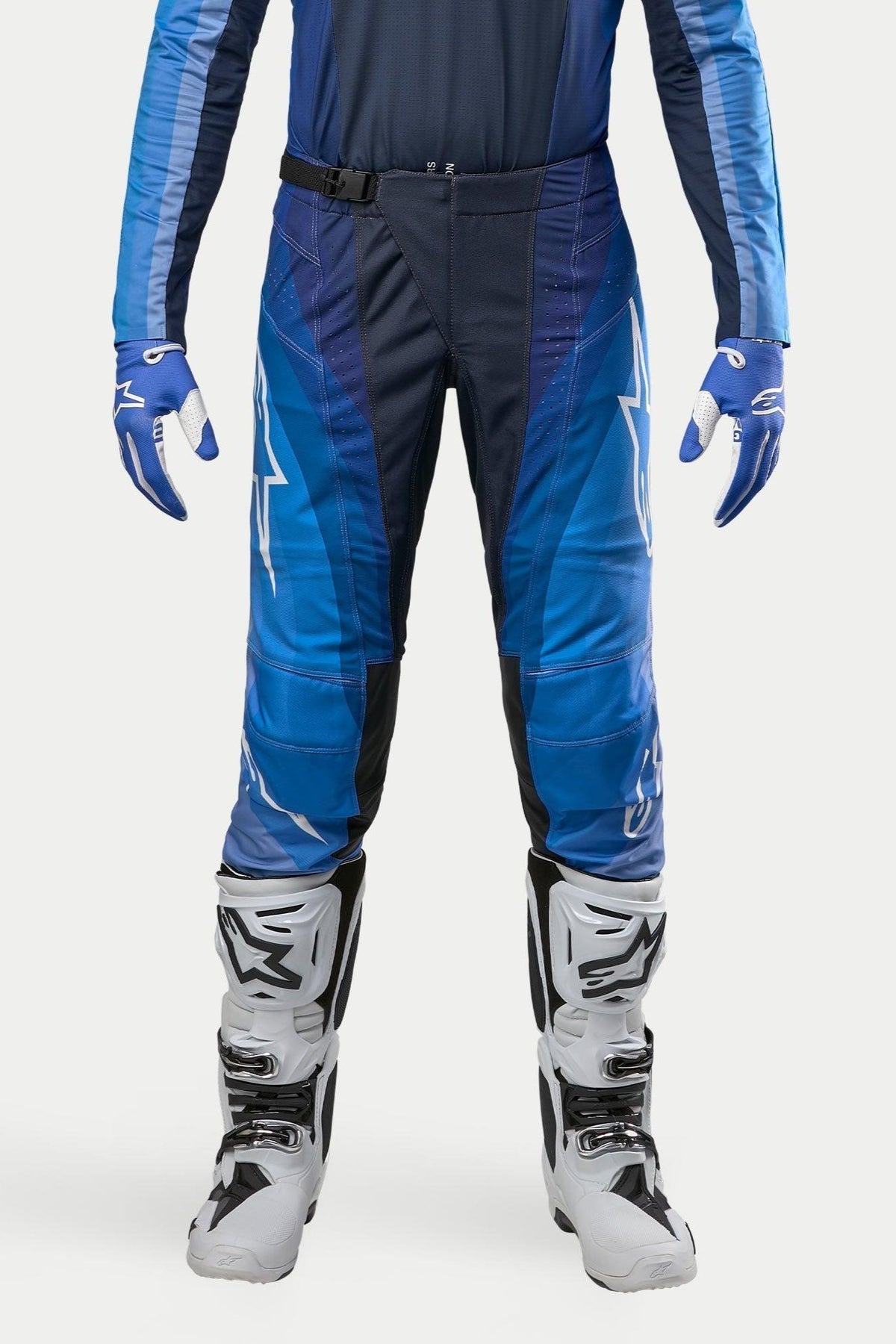 Alpinestars 2024 Techstar Pneuma Pants, Motocross Pants, Dark Navy and Light Blue, worn with matching blue jersey and white boots, featuring white Alpinestars branding and magnetic buckle closure, designed for professional off-road performance