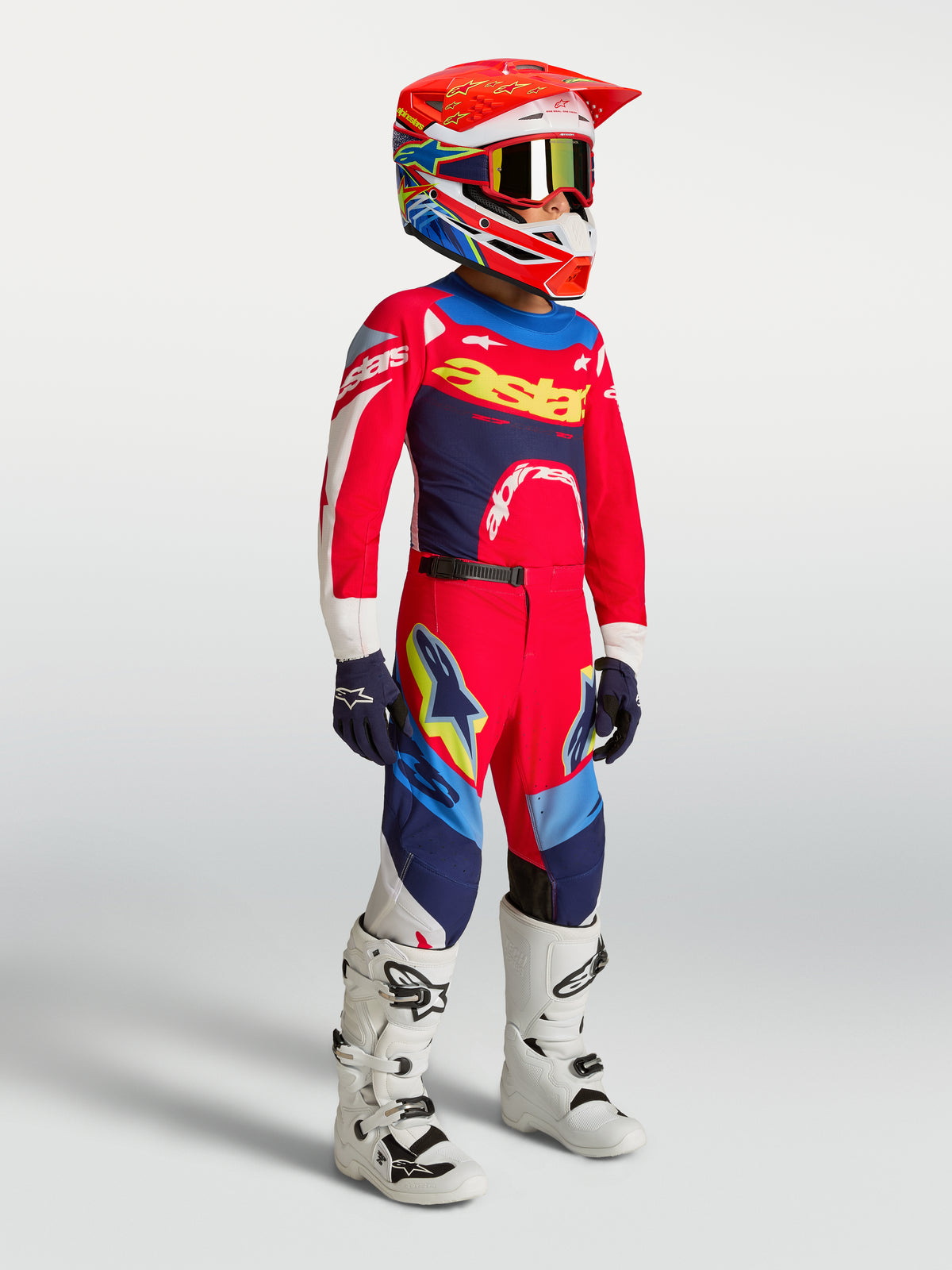 Alpinestars 2027 Supertech Dyna bukser ungdom, rød og mørkeblå motocrossbukser på model med matchende trøje og hvide støvler.