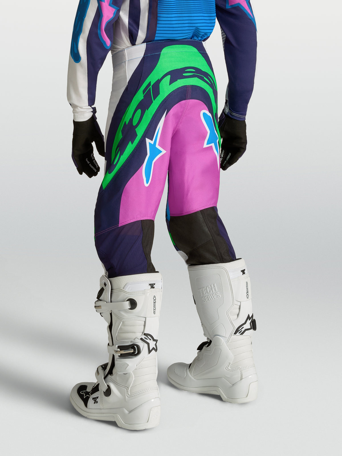 Alpinestars Supertech Maven motocrossbukser til unge, blå og pink med neongrønne logoer, atletisk racerpasform, set bagfra på model