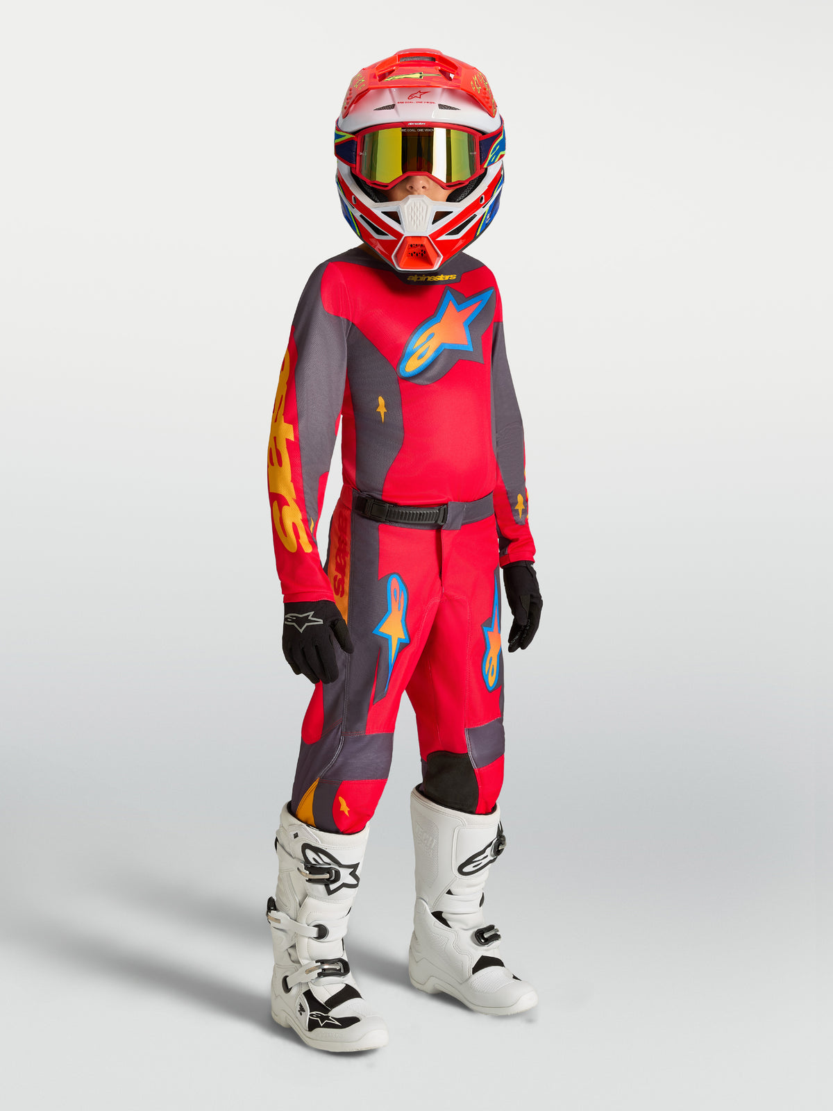 Alpinestars Youth Fluid Hunt Pants, red and gray motocross gear on-model with matching jersey, white boots, and helmet.