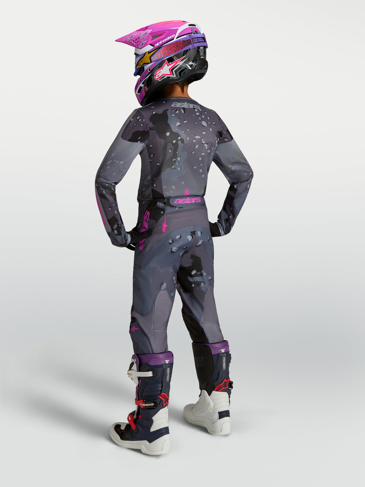 Alpinestars Ungdom Fluid Lone udstyrssæt, grå og pink motocrossudstyr, set bagfra på ung kører med hjelm og støvler.