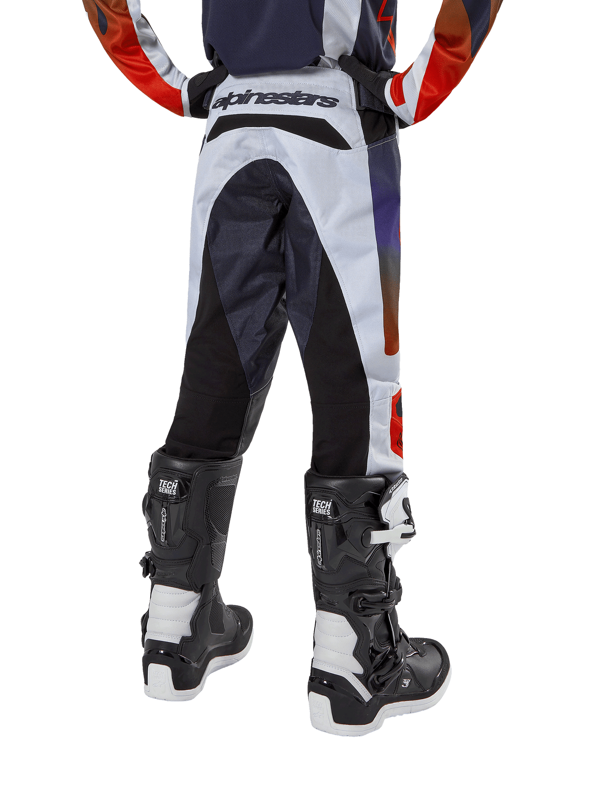 Alpinestars 2024 Youth Racer Hoen bukser, motocrossbukser til unge, lysegrå med stærk orange og sorte detaljer, set bagfra med sorte paneler på sædet og benene, markant branding på bagtaljen, båret med sort-hvide motocrossstøvler til terrænkørsel