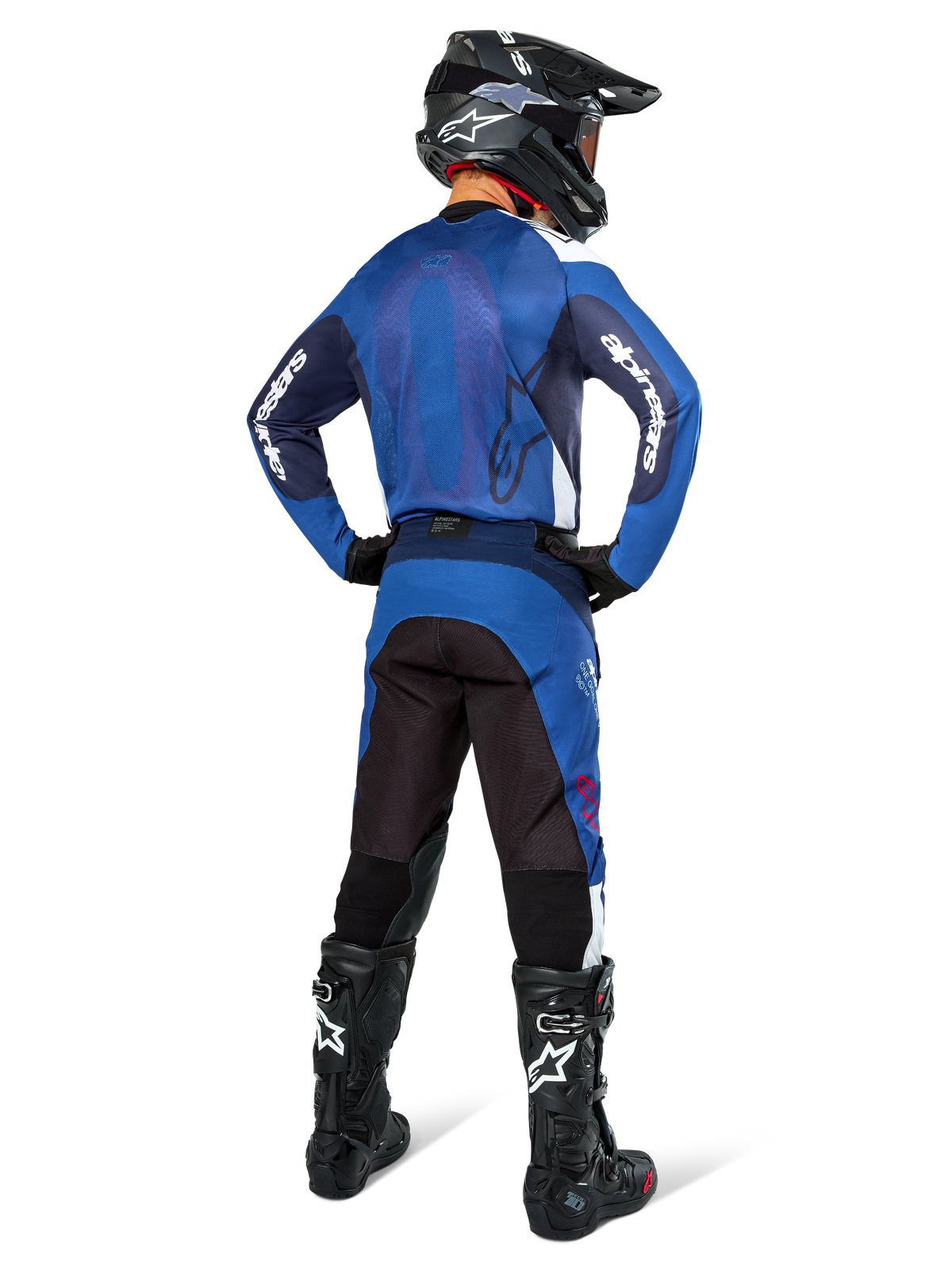Motocrossrytter set bagfra iført Alpinestars Pro-Dura trøje i navy og klar blå, matchende blå og sorte bukser, sort motocrosshjelm med goggles og sorte støvler, der viser et koordineret off-road racersæt