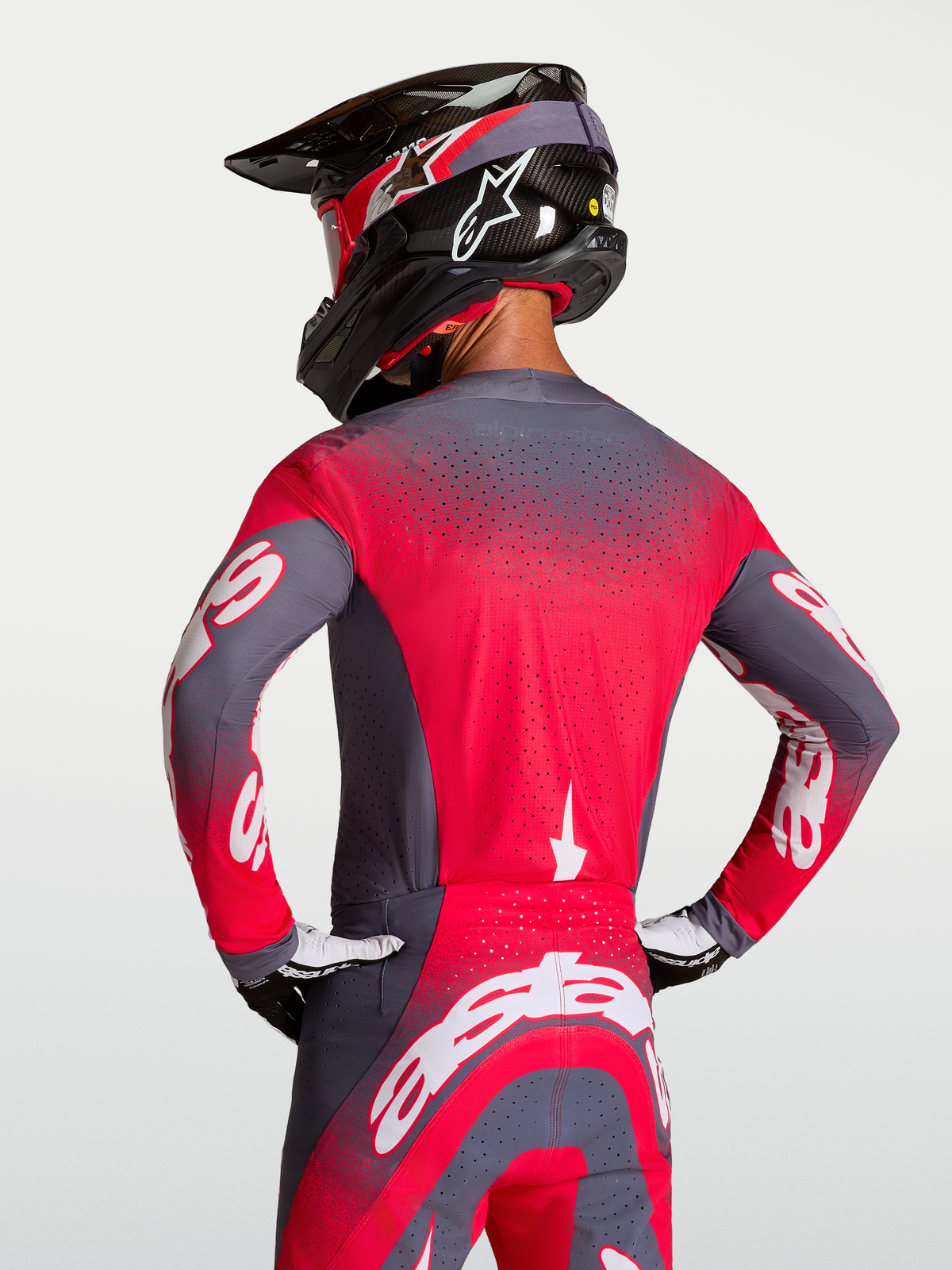 Alpinestars Supertech Hiten AFD trøje, motocross racingtrøje i grå og rød fluo, vist bagfra på rytter med Stretchnet-ventilation og atletisk pasform