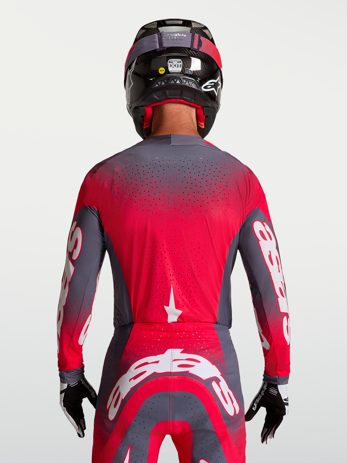 Alpinestars Supertech Hiten AFD trøje, grå og rød fluo motocrosstrøje, ventileret mesh-konstruktion med laserskårne perforeringer, set bagfra på model med hjelm, atletisk pro racing-pasform til MX.
