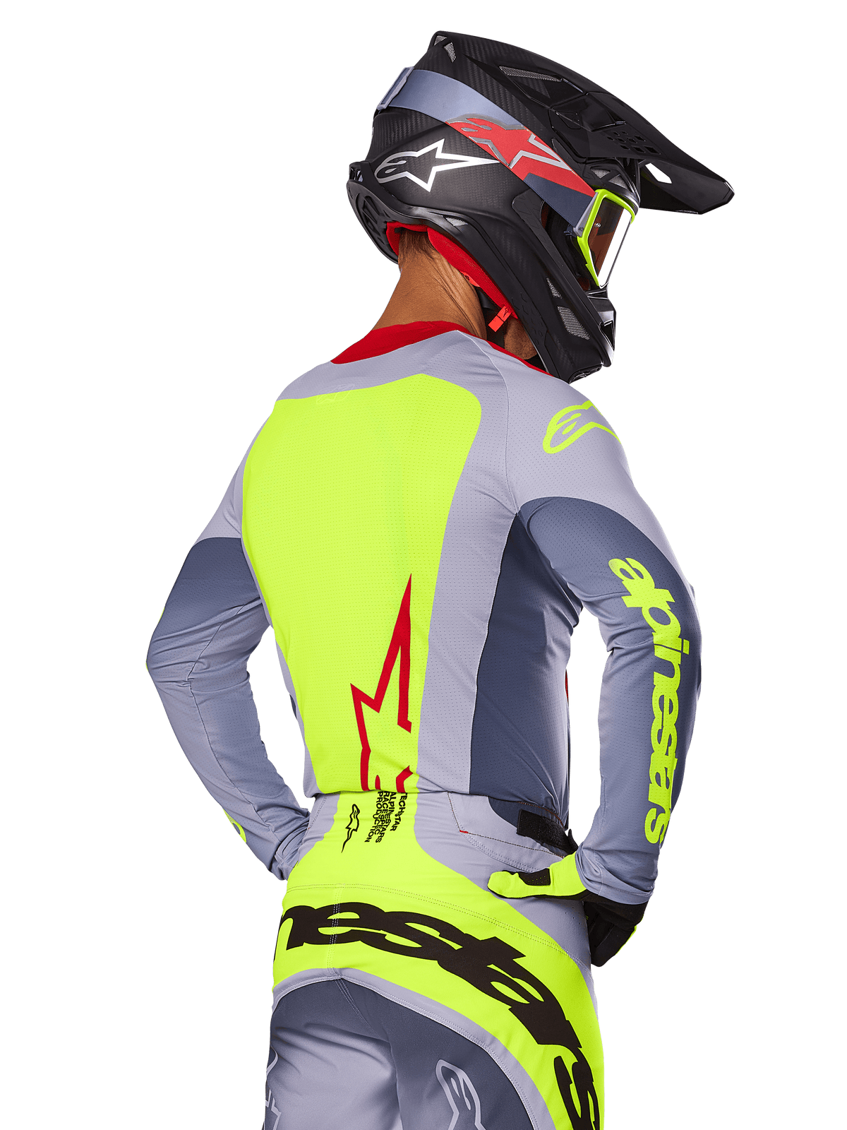 Alpinestars 2025 Techstar Melt Jersey, Bright Red Gray, set bagfra af motocrosskører iført gråt og neongult racerudstyr, rødt stjernelogo på ryggen, matchende sort og rød hjelm, højtydende off-road beklædning