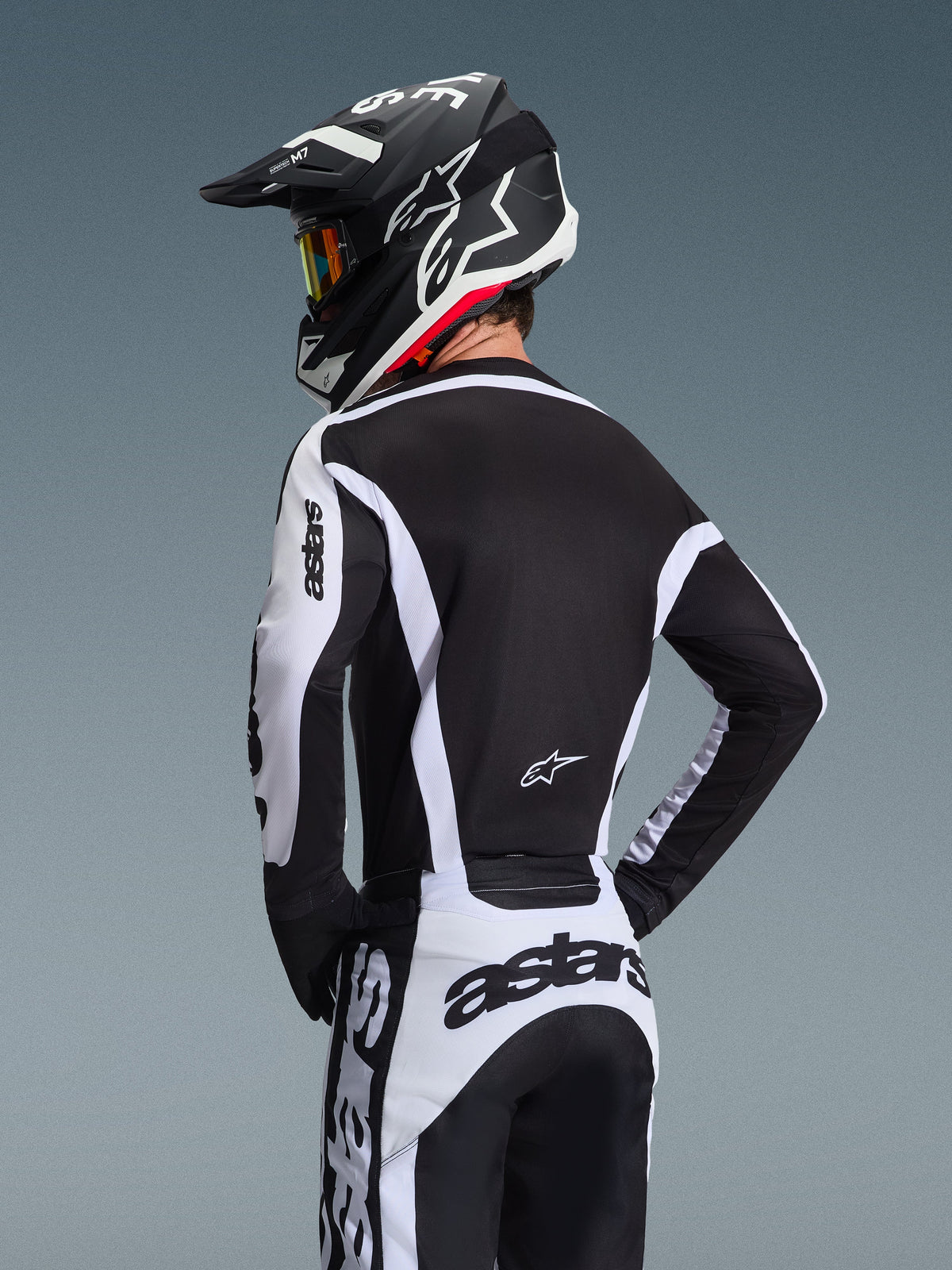Alpinestars 2026 Racer Riway udstyrssæt, motocrosskører set bagfra iført sort og hvid teknisk trøje og bukser, matchende sort og hvid hjelm med briller, markant astars-branding på ærmer og ryg, designet til off-road-performance