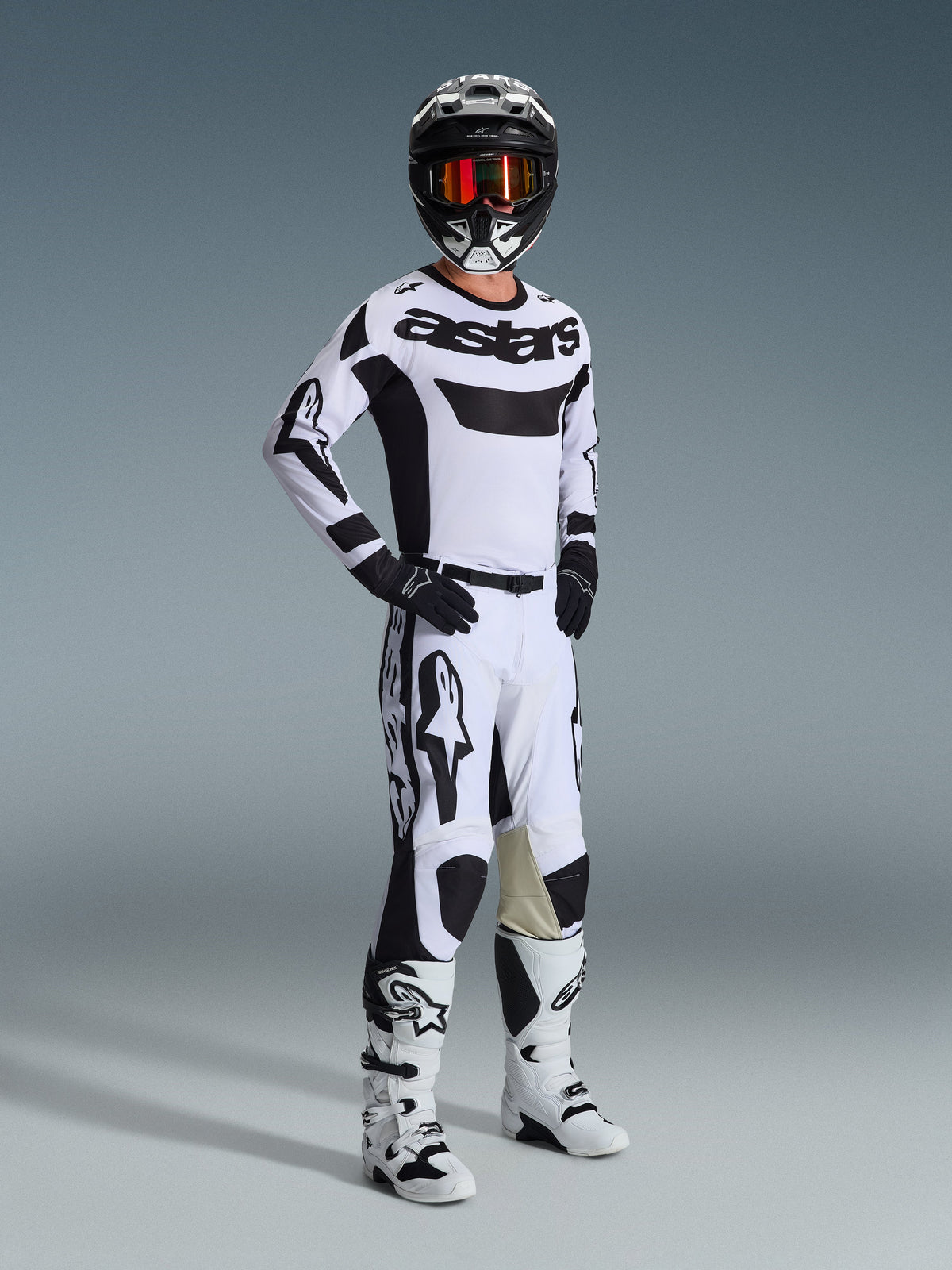 Alpinestars 2026 Racer Riway Gear Set, motocross-kører i hvidt og sort racersæt, hvid trøje med sort 'astars' logo på brystet, hvide bukser med sorte detaljer, sort hjelm med orange goggles, hvide støvler, koordineret udstyr til motocross og terrænkørsel
