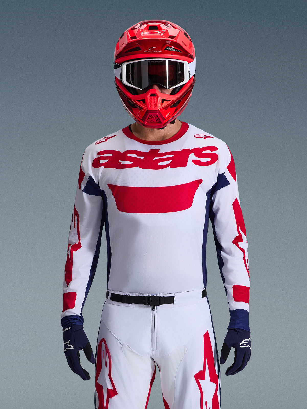 Alpinestars 2026 Racer Riway Gear Set, motocross-kører iført hvid trøje med rød branding og mørkeblå detaljer, matchende hvide bukser med rød grafik, rød hjelm med hvide goggles, mørkeblå handsker, professionelt koordineret terrænkørselsudstyr.