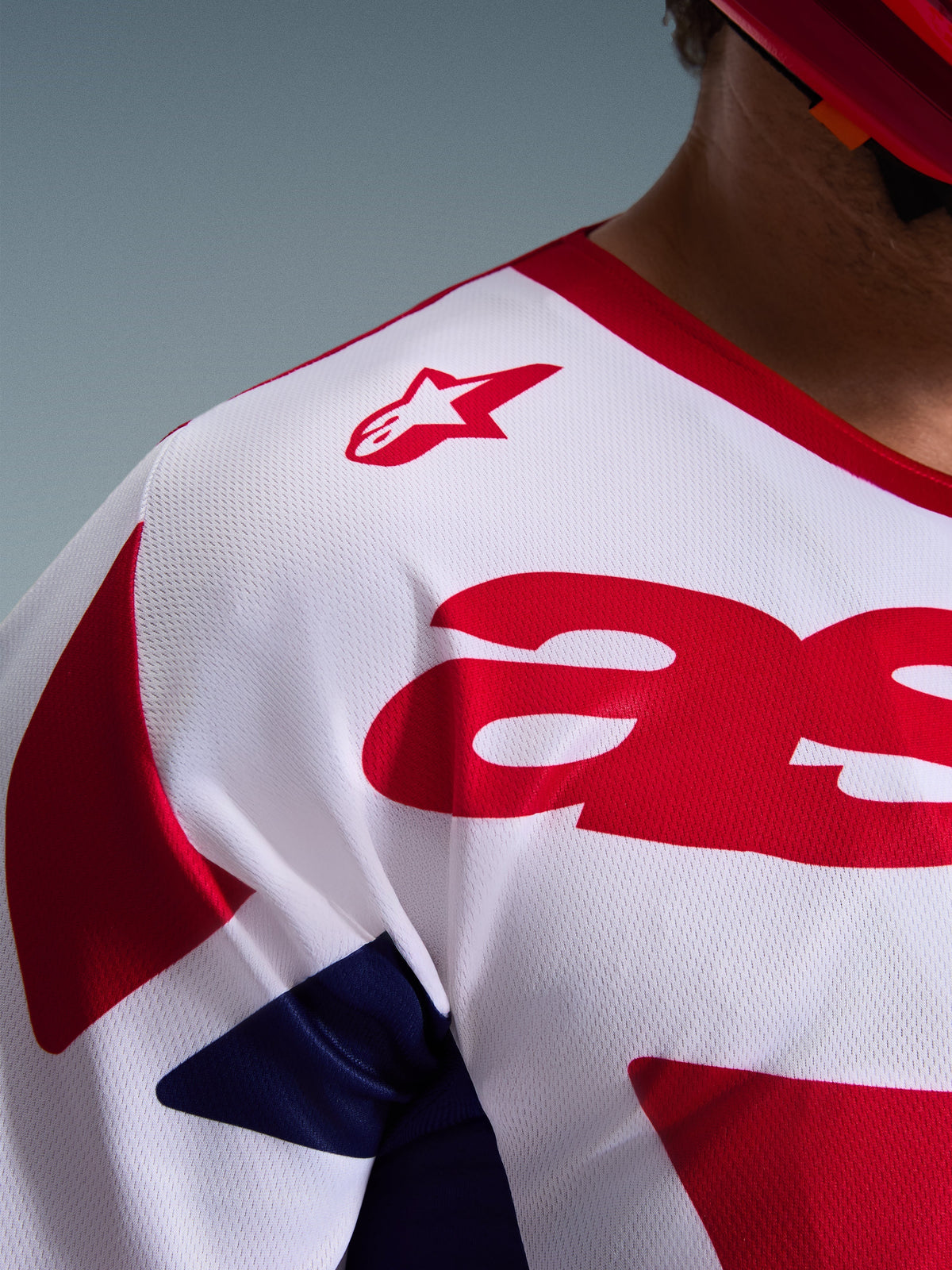Nærbillede af Alpinestars 2026 Racer Riway Jersey i hvid, blå og rød, der fremhæver den åndbare mesh-polyfabric-konstruktion, det røde Alpinestars-logo på skulderen og det fugttransporterende materiale til off-road kørsel.