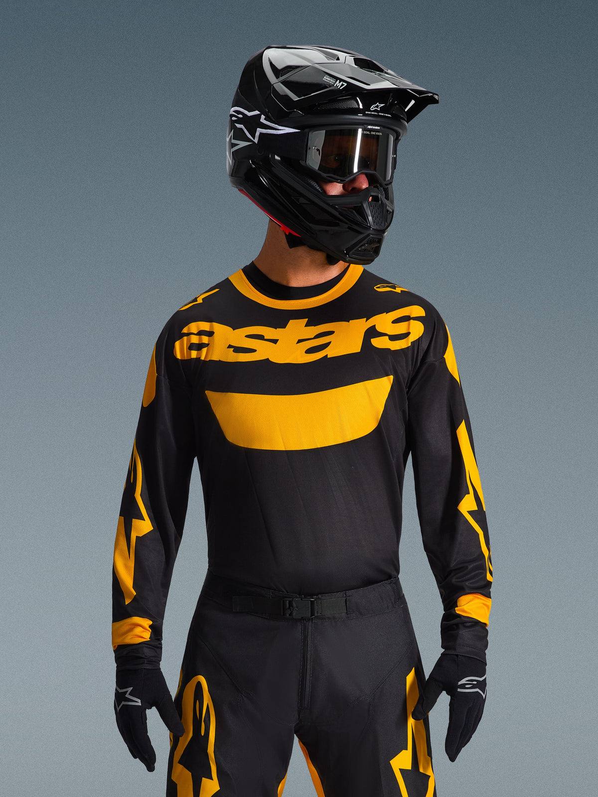 Alpinestars 2026 Racer Riway Gear Set, motocross rider wearing black jersey with bold yellow 'astars' logo, matching black pants with yellow accents, black helmet and goggles, black gloves, professional off-road racing gear