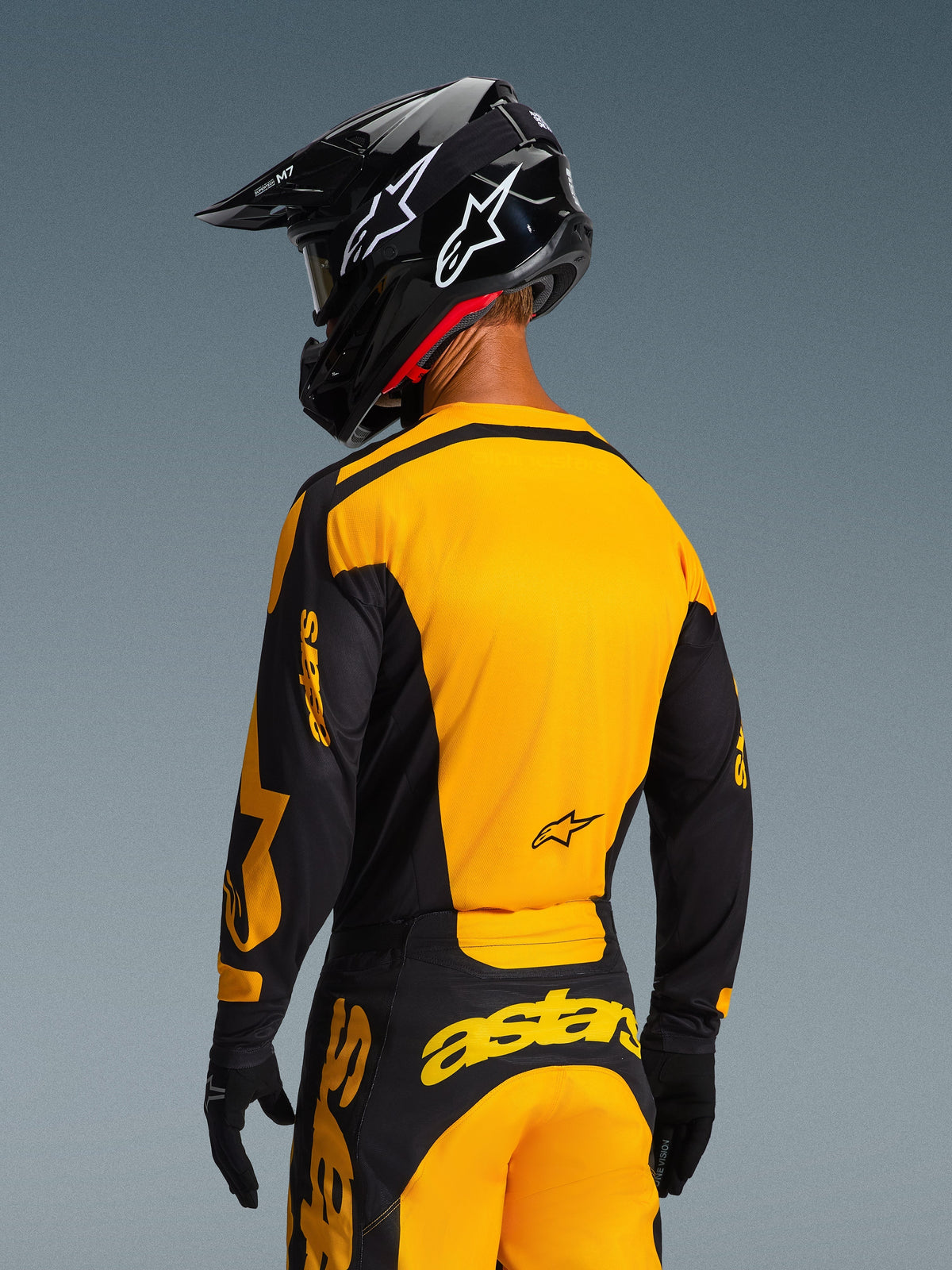 Set bagfra af en motocross-kører iført Alpinestars 2026 Racer Riway Jersey i gul og sort, med et markant gult rygpanel og sorte ærmer med gul branding, kombineret med matchende motocross-bukser og en sort hjelm for et komplet off-road racersæt.