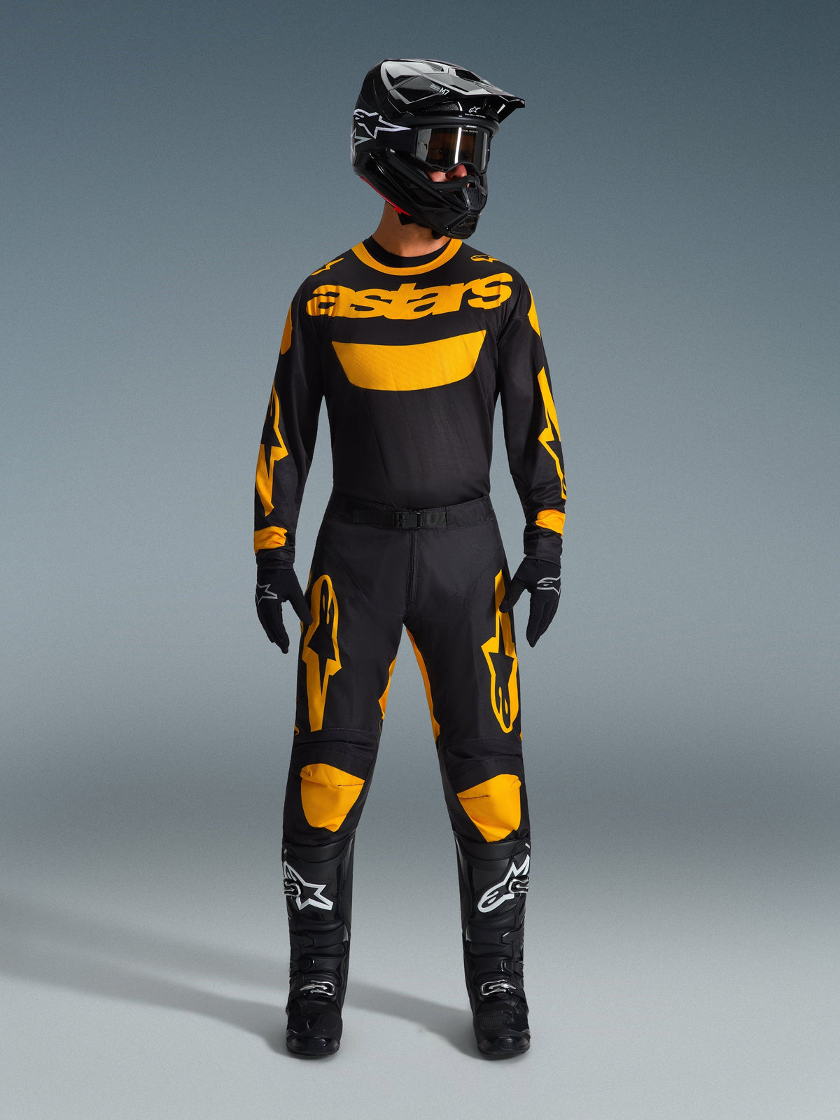Motocross-rytter iført 2026 Racer Riway Jersey i gul og sort, matchet med tilhørende bukser, sort hjelm og sorte støvler med hvide Alpinestars-logoer, komplet udstyrssæt til off-road racing.