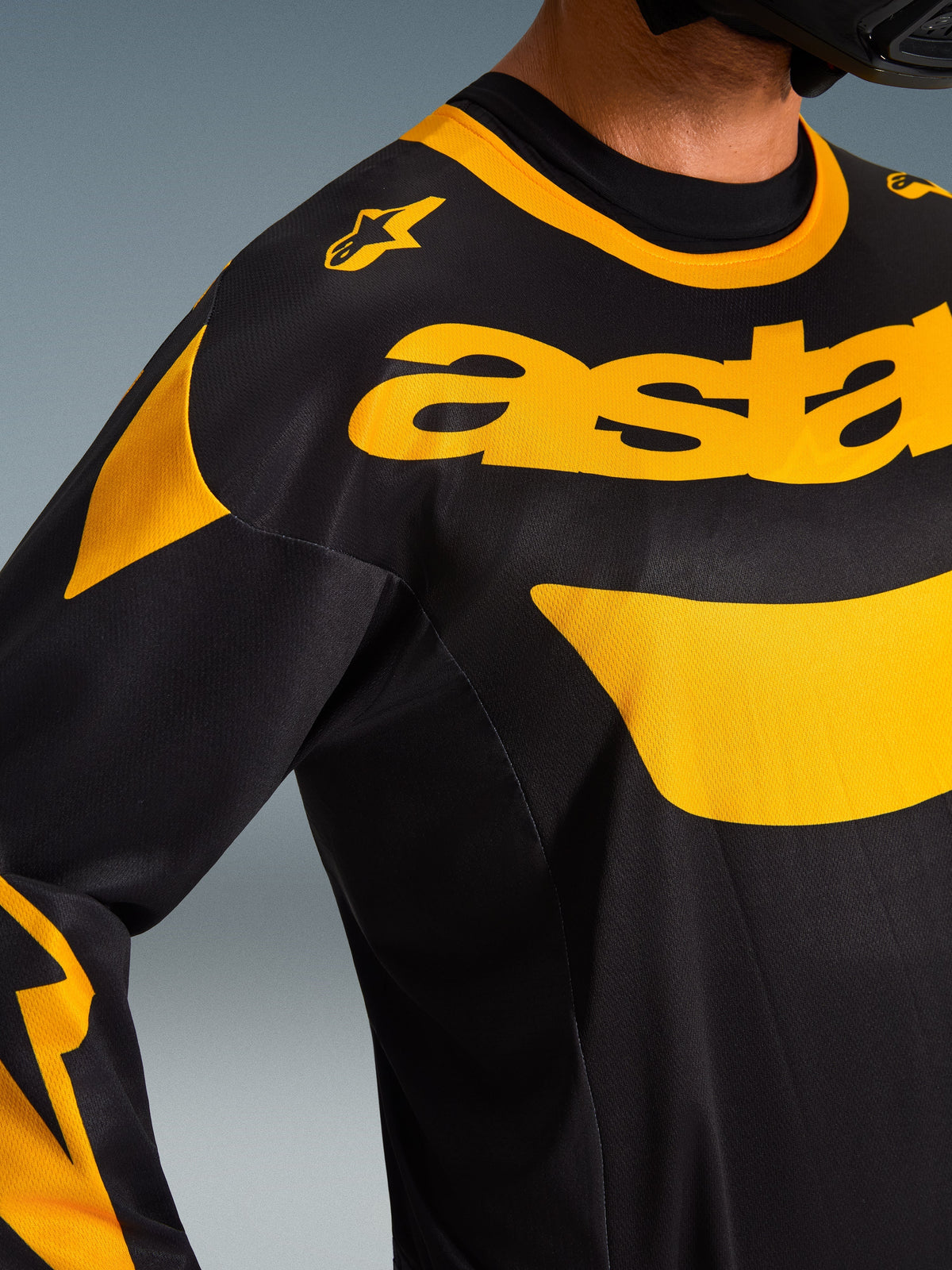 Alpinestars 2026 Racer Riway Jersey, motocrosstrøje, gul og sort, nærbillede af bryst- og skulderområdet med markant gul 'astars'-branding og grafiske detaljer på sort polyfabric, performance off-road-udstyr