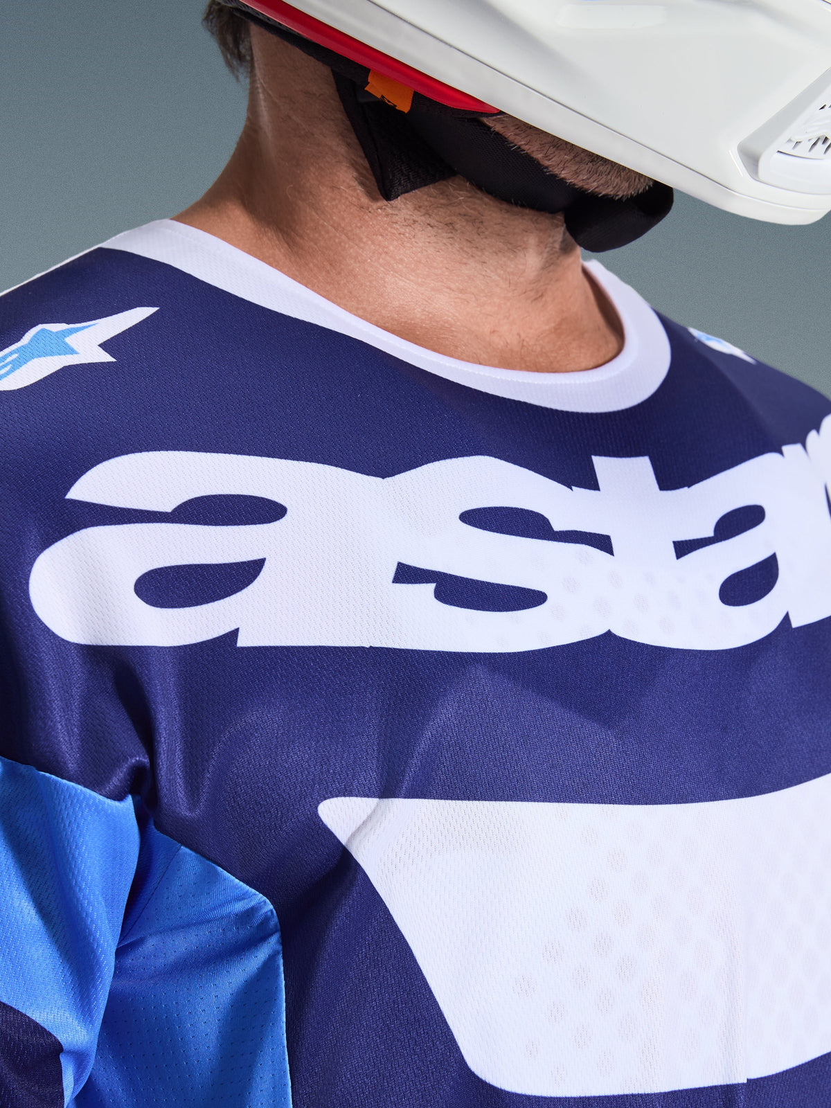 Alpinestars 2026 Racer Riway trøje, motocross trøje, UCLA Blue og hvid, nærbillede af brystet med stort hvidt 'astars' branding, hvid krave og fugttransporterende mesh-tekstur, båret med en hvid hjelm