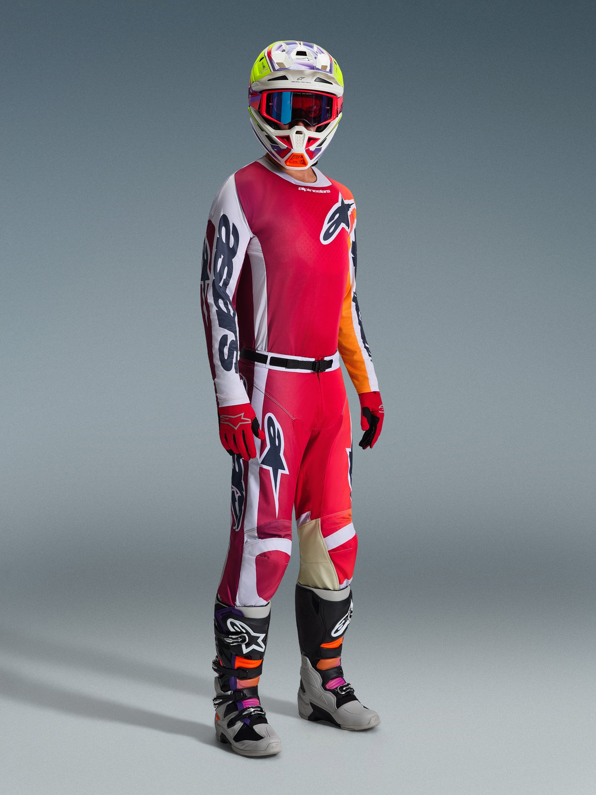 Motocrosskører iført Alpinestars 2026 Racer Portl Gear Set, bestående af en rød og hvid trøje med markant 'Astars' branding på ærmet, matchende røde og hvide bukser, en koordineret hvid og gul hjelm med rødindfattede goggles og grå og sorte motocrossstøvler, komplet outfit til off-road racing.