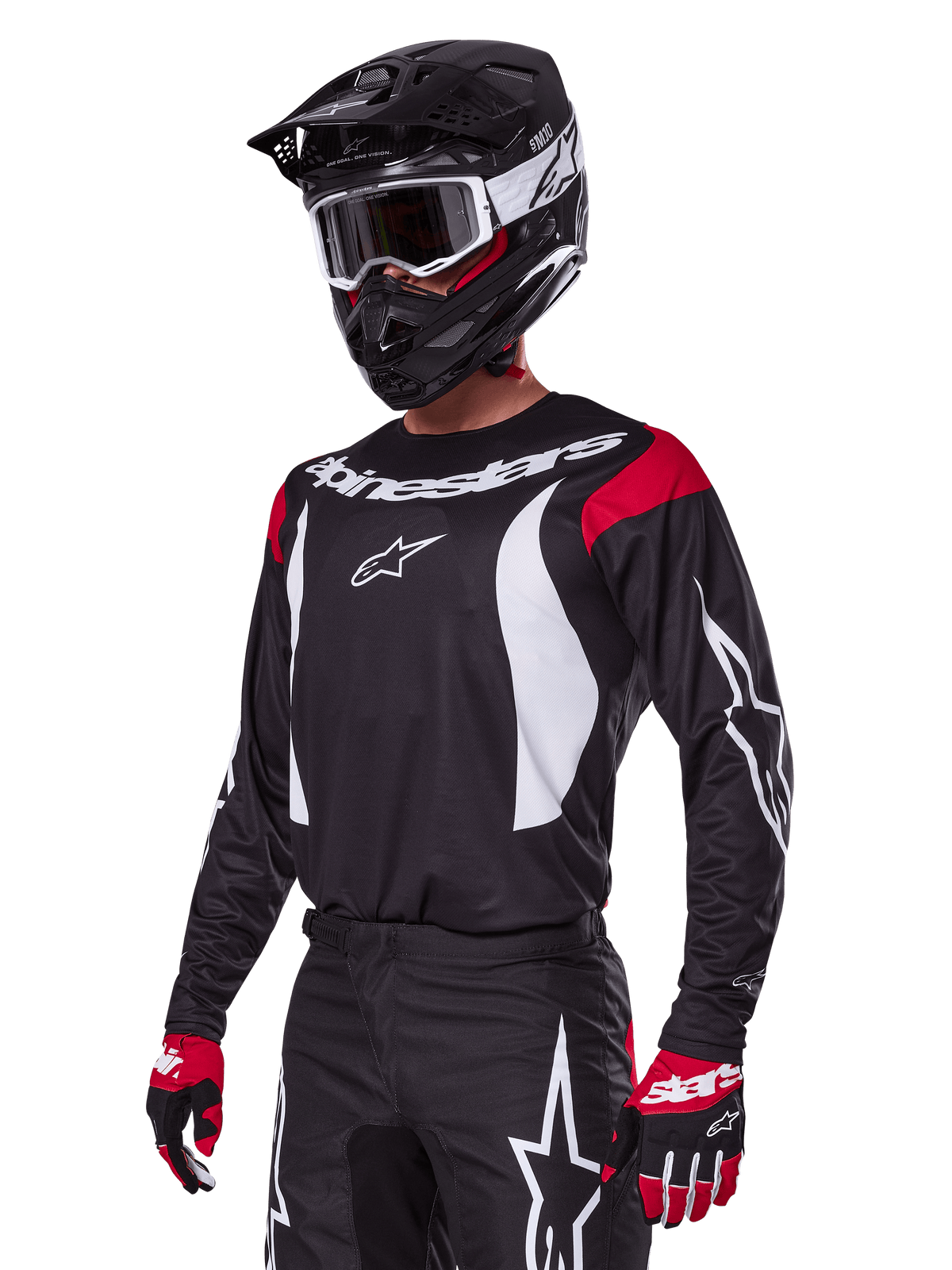 Motocross rider wearing Alpinestars 2025 Fluid Haul Gear Set, black jersey with red shoulder panels and white graphics, matching black pants with white star logos, red and black gloves, black helmet with white accents and goggles, coordinated motocross apparel.