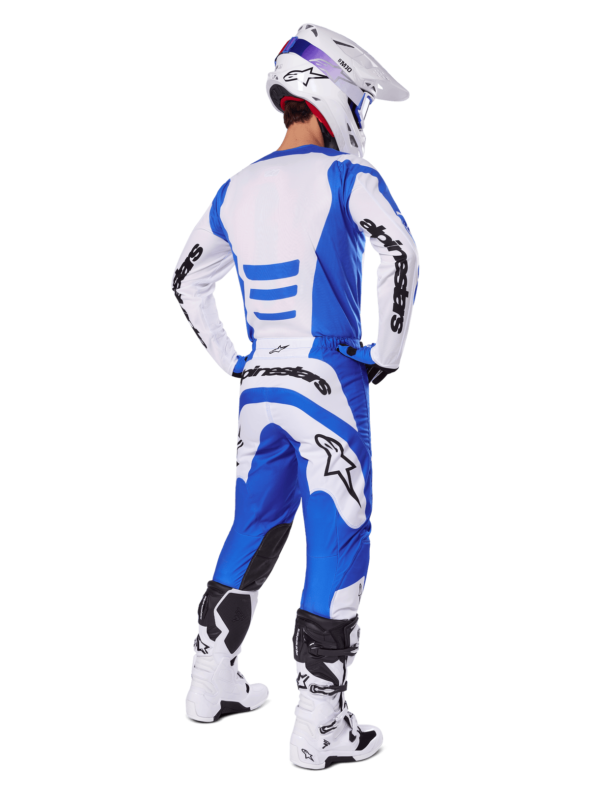 Motocrossrytter set bagfra iført Alpinestars 2025 Fluid Haul-udstyrssæt, blå og hvid trøje med matchende bukser, hvid hjelm med blå detaljer og hvide og sorte racingstøvler, koordineret off-road racing-outfit