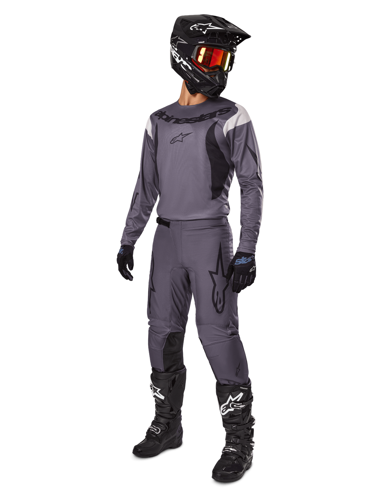 Motocross-kører iført Alpinestars 2025 Fluid Haul Gear Set i grå, inklusiv grå jersey og bukser med sorte detaljer, sort hjelm med rødlige goggles, sorte handsker og sorte støvler med hvide logoer, komplet off-road raceroutfit