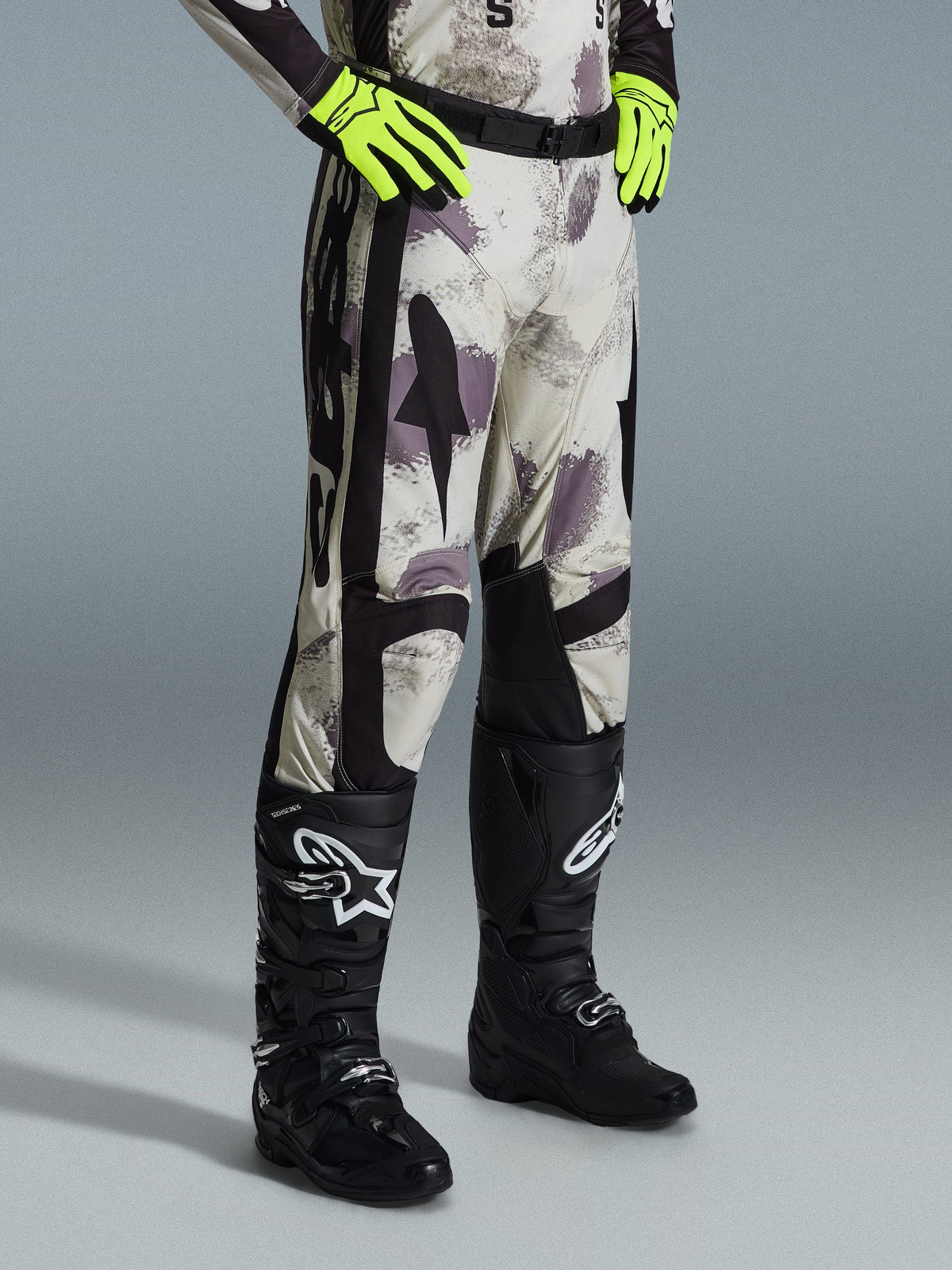 Alpinestars 2026 Racer Lahnd bukser, motocrossbukser, Sand Camo, båret med neongule handsker og sorte motocross-støvler, med abstrakt camouflage-mønster og sorte sidepaneler, ergonomisk off-road-design