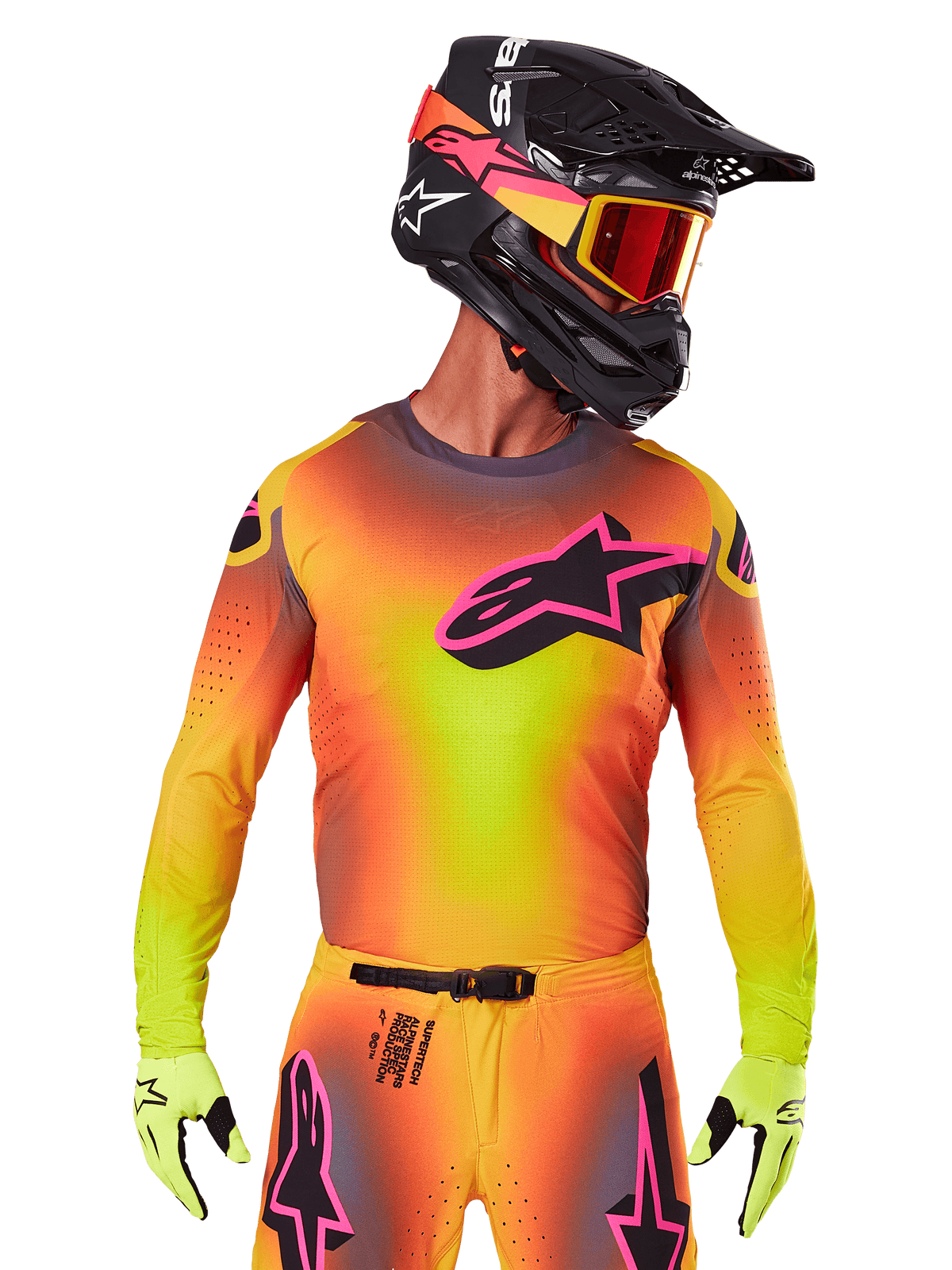 Motocross-rytter iført 2025 Supertech Lipan-trøjen, livlig gul, orange og pink gradient, stort sort Alpinestars stjerne-logo med pink omrids på brystet, laserskårne perforeringer til ventilation, atletisk race-pasform, kombineret med matchende bukser, gule handsker og sort hjelm med goggles.