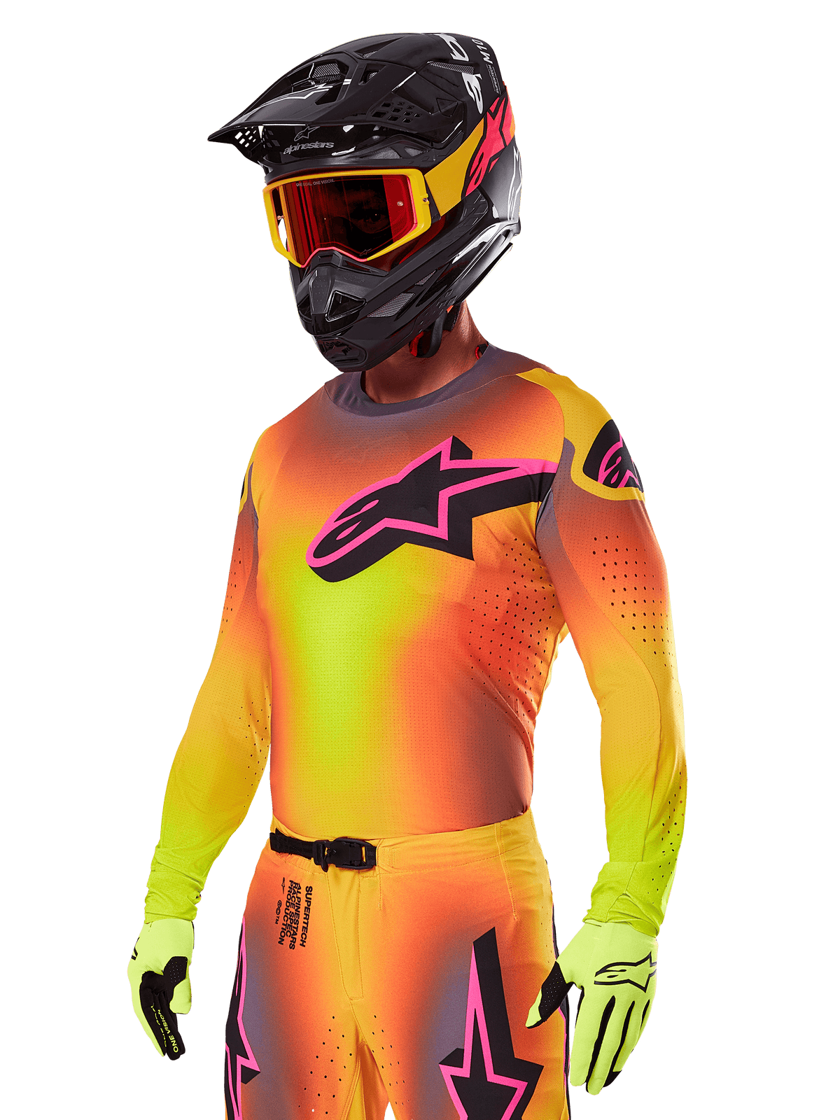 Motocrosskører iført Alpinestars 2025 Supertech Lipan-udstyrssæt, med en jersey med gul og orange farveovergang og et lyserødt og sort Astars-logo, neongule handsker og en sort hjelm med røde briller, professionelt terrænkørselsudstyr.