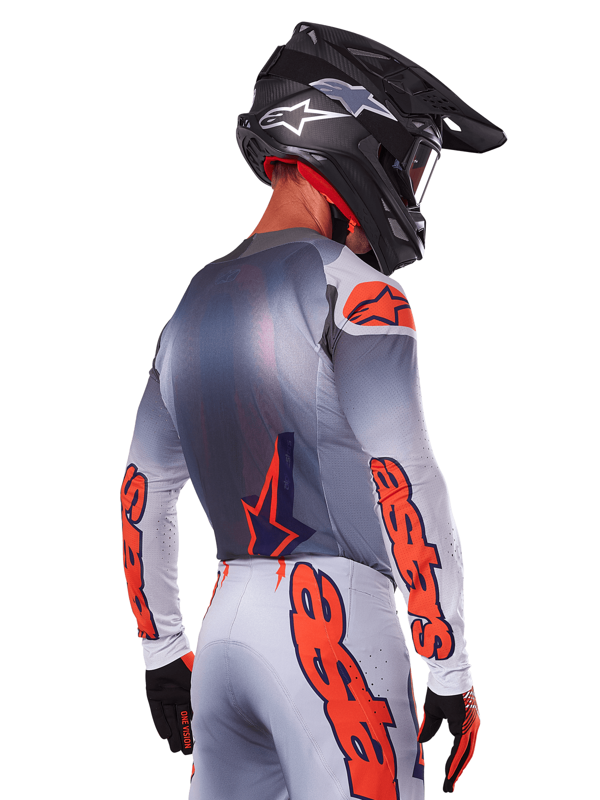 Motocrosskører set bagfra iført Alpinestars 2025 Supertech Lipan-jersey i Gray Orange Fluo, med markante orange logoer på ærmerne og ryggen, kombineret med matchende bukser og en sort hjelm, professionelt racerudstyr til terrænkørsel.