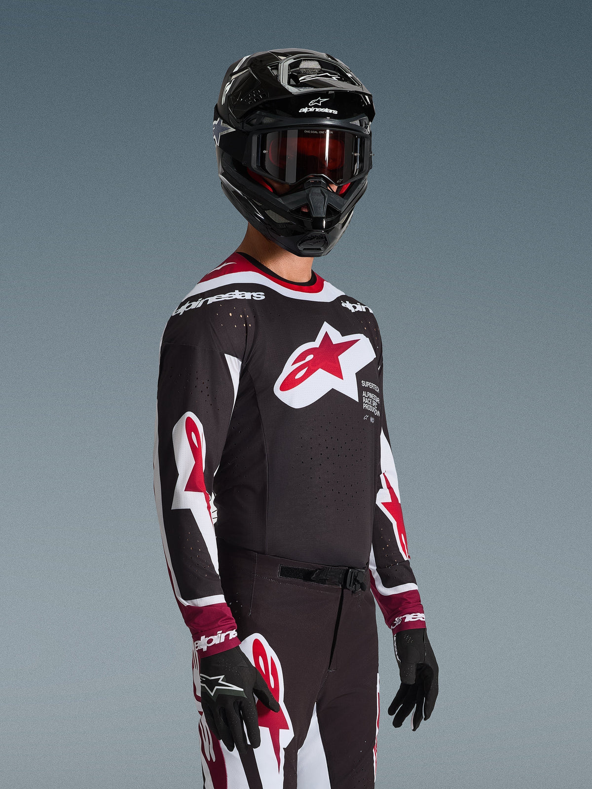 Motocrosskører iført Alpinestars 2026 Supertech AFD Vista Jersey i sort, rød og hvid, med et stort rødt stjernelogo på brystet og laserskårne perforeringer, kombineret med en sort hjelm og matchende racerbukser til off-road kørsel