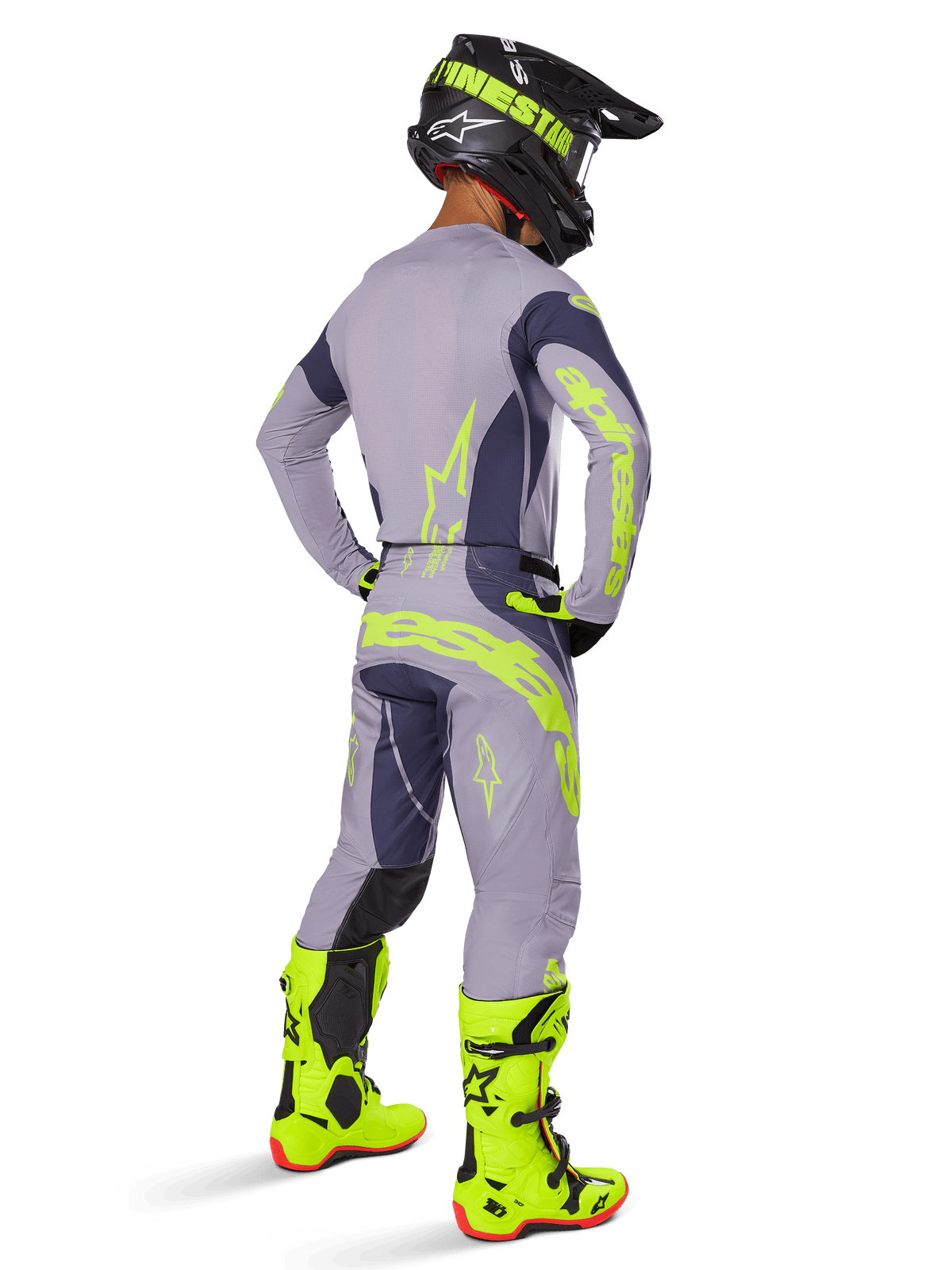 Motocrosskører set bagfra iført Alpinestars 2025 Techstar Dreem-udstyrssæt, grå og mørkegrå med fluorescerende gul branding, matchende trøje og bukser, sort hjelm med gule detaljer og klare fluorescerende gule støvler, koordineret professionelt motocross-raceroutfit.
