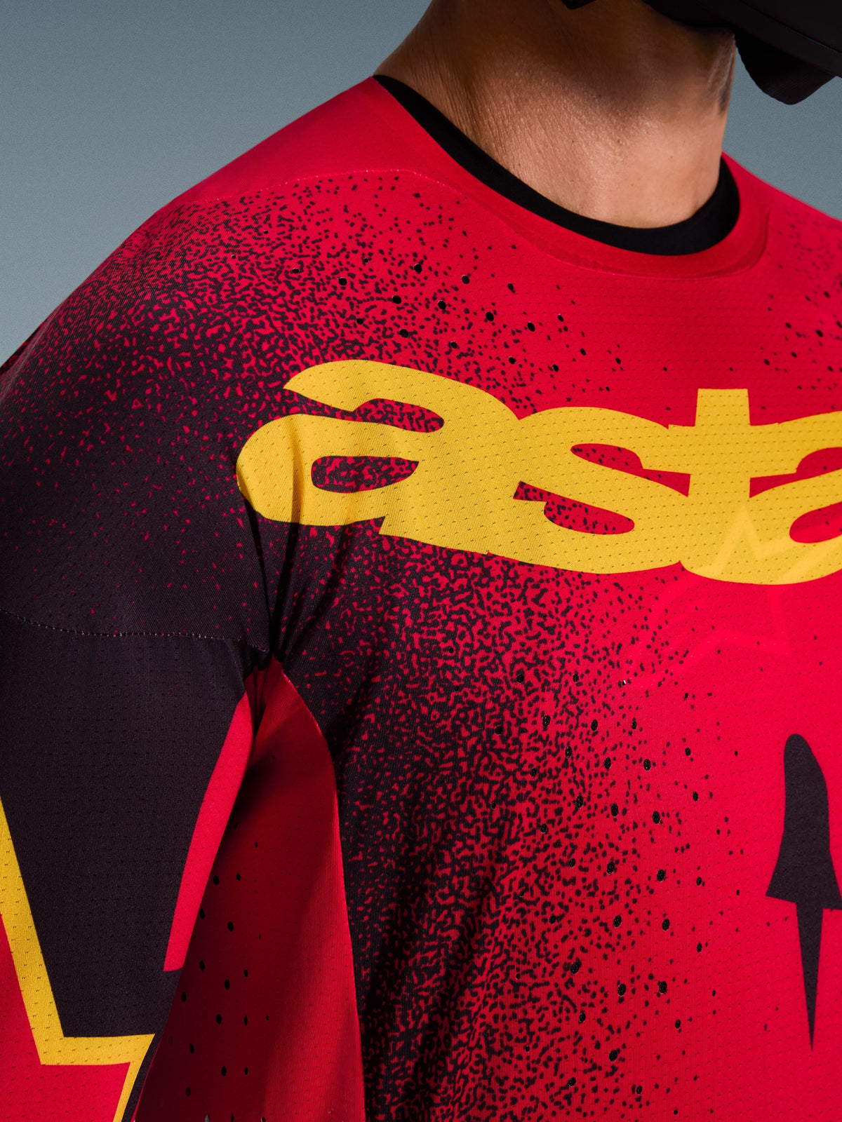 Nærbillede af Alpinestars 2026 Supertech Scenz trøje i Red Black Yellow, med et stort gult logo på brystet, laser-skårne perforeringer for øget luftstrøm og en letvægts mesh-tekstur til professionel motocross-racing.