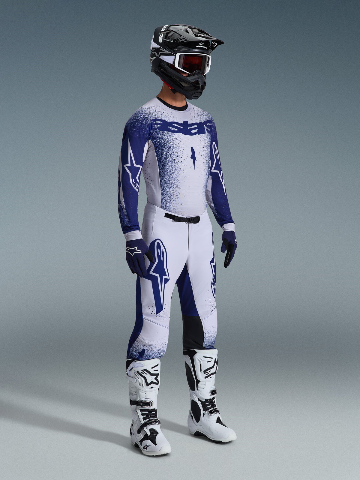 Alpinestars 2026 Supertech Scenz Gear Set, motocross-udstyr, hvid og marineblå racertrøje og bukser med gradueret prikeffekt, markant Astars-branding, kombineret med sort og hvid hjelm, marineblå handsker og hvide motocross-støvler.