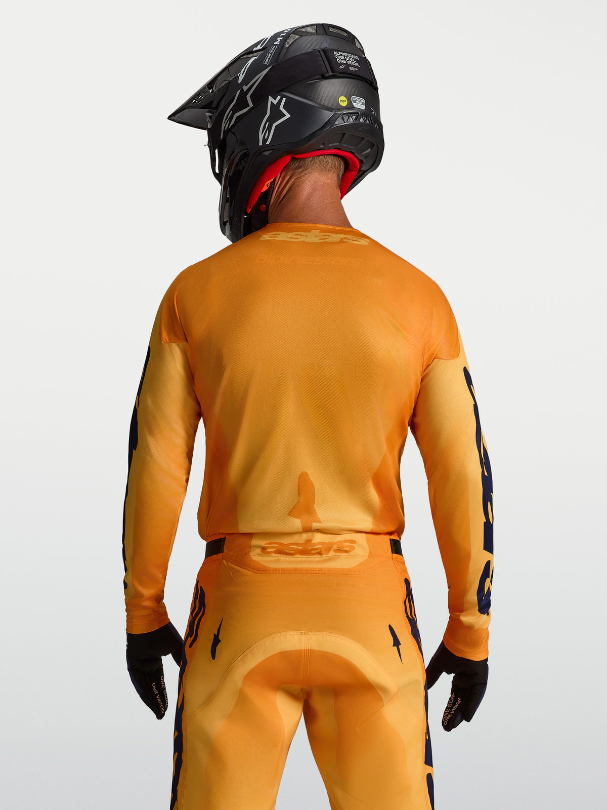 Alpinestars Racer Amber trøje, herre-motocrosstrøje i orange og guld med åndbare mesh-paneler, vist bagfra på model.