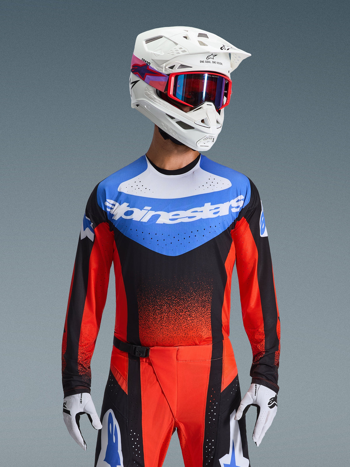 Alpinestars 2026 Techstar Knif Gear Set, motocross-racerudstyr med en blå, hvid, sort og rød trøje med Alpinestars-branding, matchende røde og sorte bukser, båret med en hvid hjelm, røde briller og hvide handsker, atletisk pasform til off-road-konkurrence