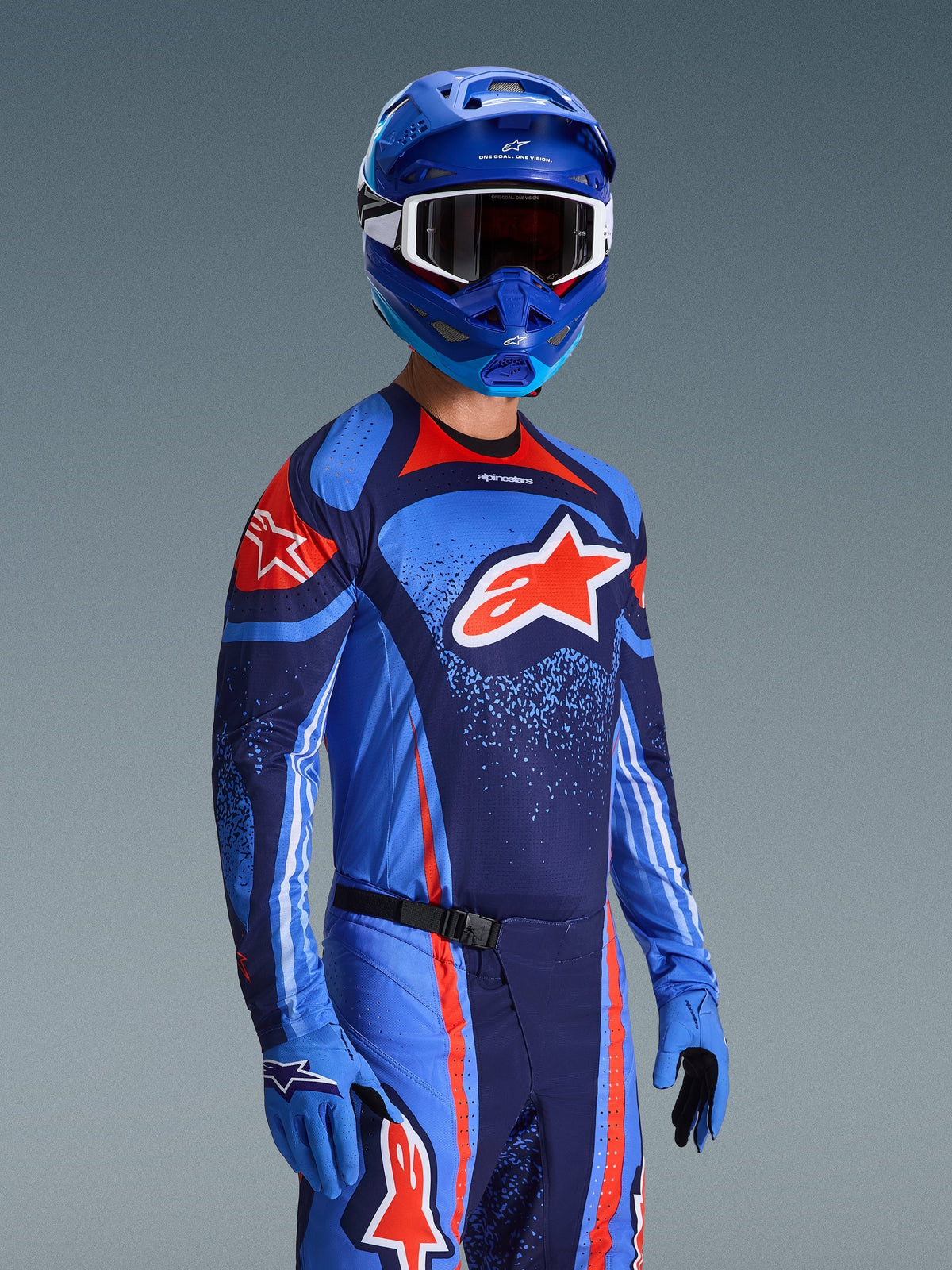 Alpinestars 2026 Techstar Nomur udstyrssæt, motocross-trøje og -bukser i mørk navy, orange og UCLA-blå, båret af en kører med matchende blå hjelm og handsker, med iøjnefaldende logografik og atletisk race fit.