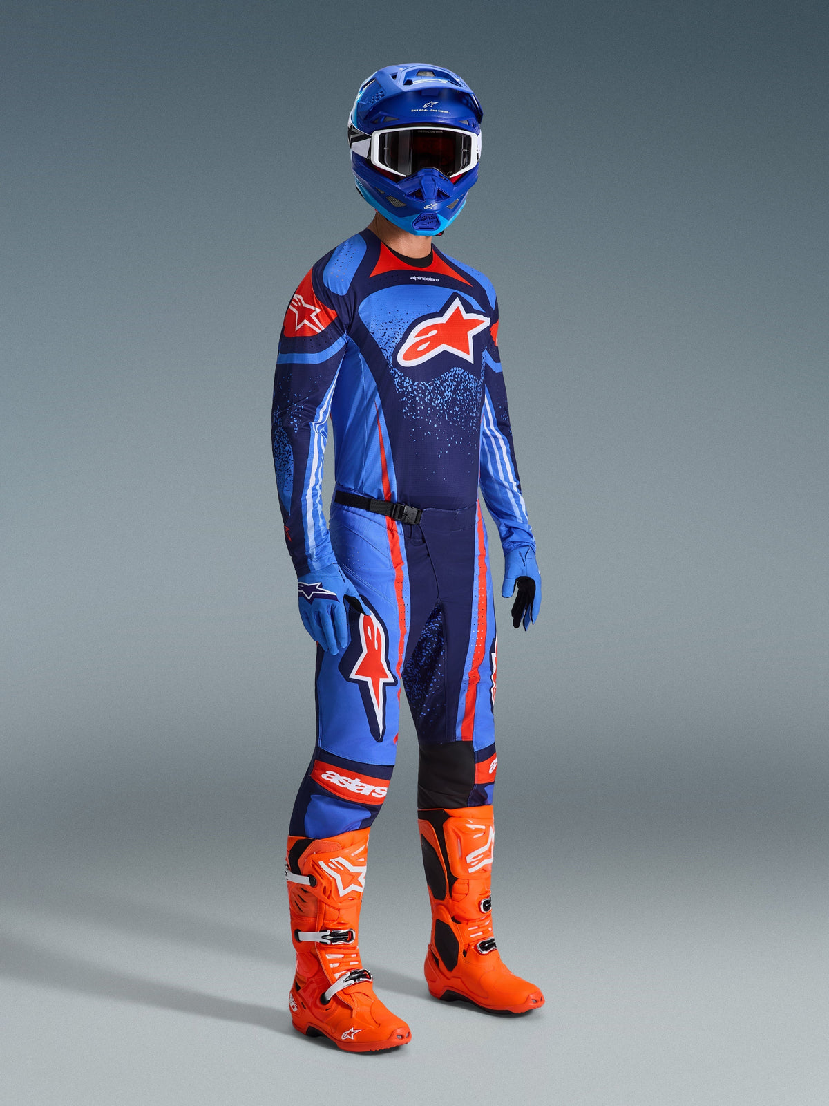 Motocross-kører iført 2026 Techstar Nomur Gear Set, mørkeblå trøje med lyseblå og orange detaljer, matchende bukser med orange striber, blå racerhjelm, stærke orange støvler og blå handsker, koordineret motocross-outfit til off-road ydeevne