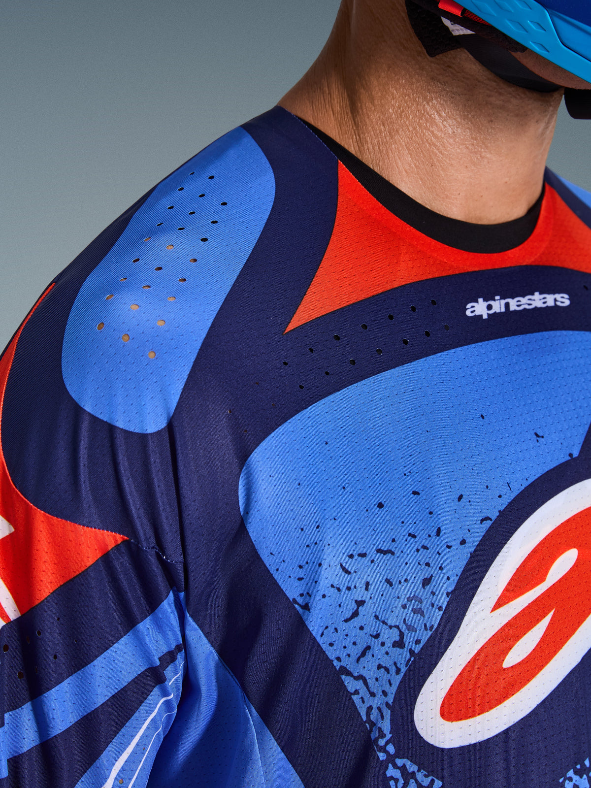 Alpinestars 2026 Techstar Nomur trøje, nærbillede af bryst- og skulderområdet, marineblåt og rødt design med laserskårne ventilationshuller, teknisk poly-tekstil til motocross-performance