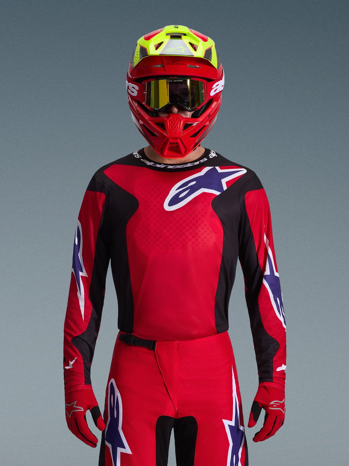 Alpinestars 2026 Fluid Grid trøje, motocross-trøje, rød, sort og lilla, båret af en kører med rød og neongul hjelm og guldbriller, med store stjernelogoer på brystet og ærmerne, koordineret udstyr til terrænkørsel